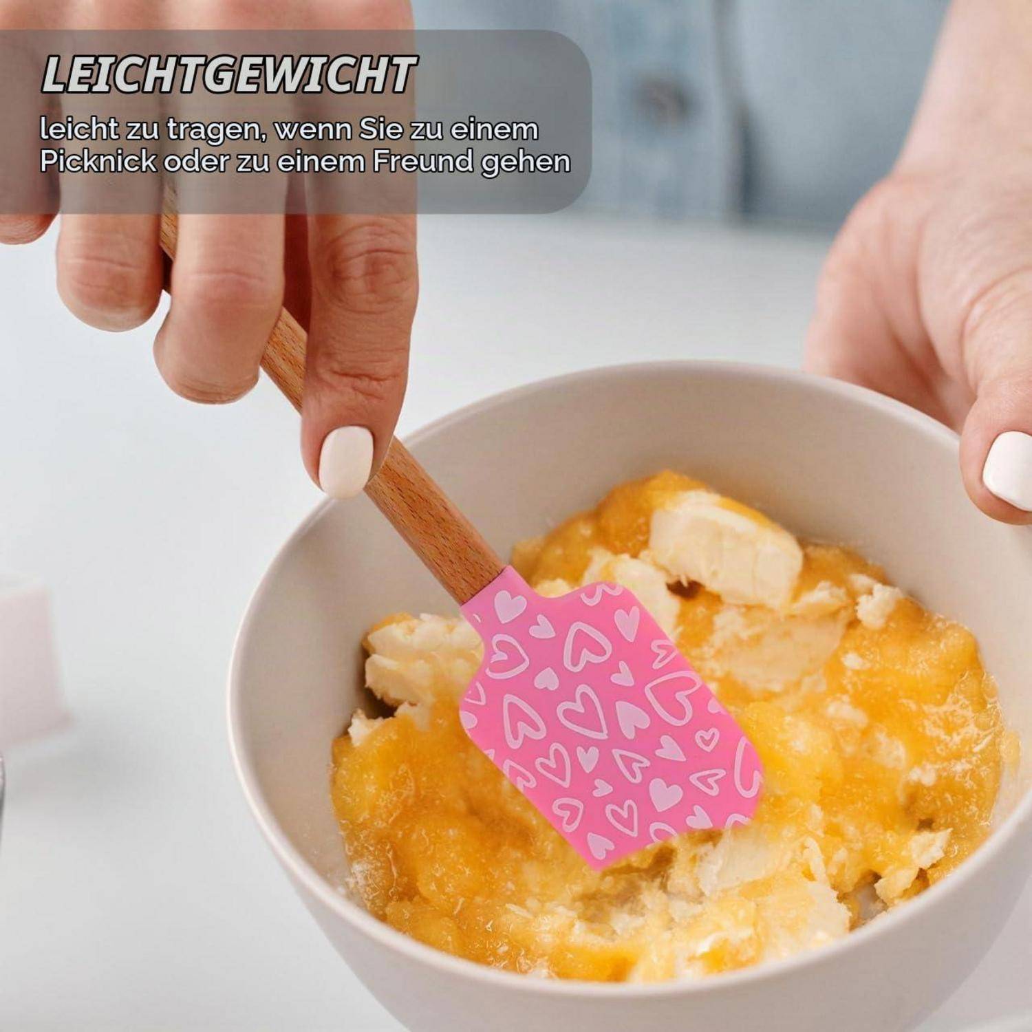 Eine Hand rührt Essen in einer Schüssel mit einem rosa herzgemusterten Spatel um; deutscher Text sagt „LEICHTGEWICHT