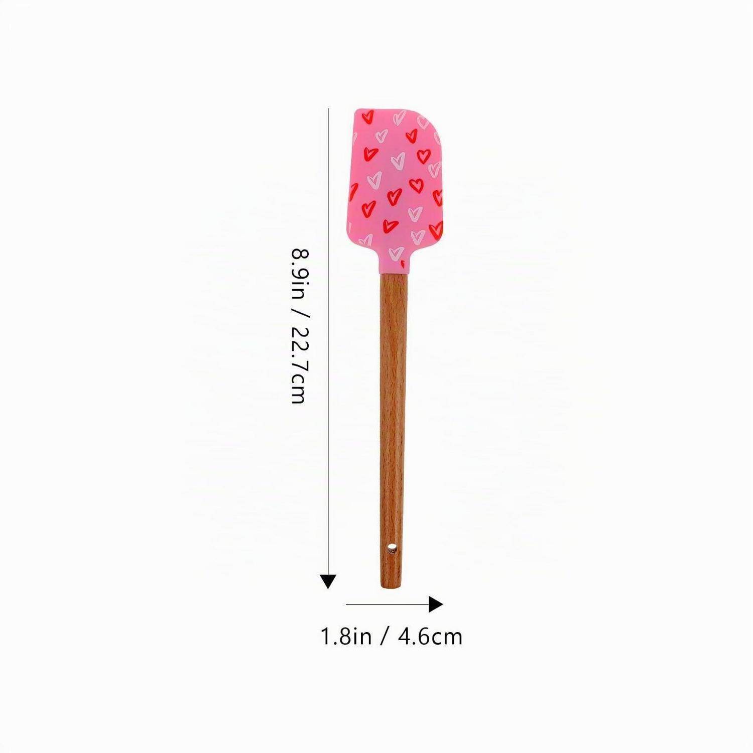 Rosa Teigschaber mit Herzmuster und Holzgriff, mit Abmessungen: 8,9 Zoll (22,7 cm) Höhe und 1,8 Zoll (4,6 cm) Breite.