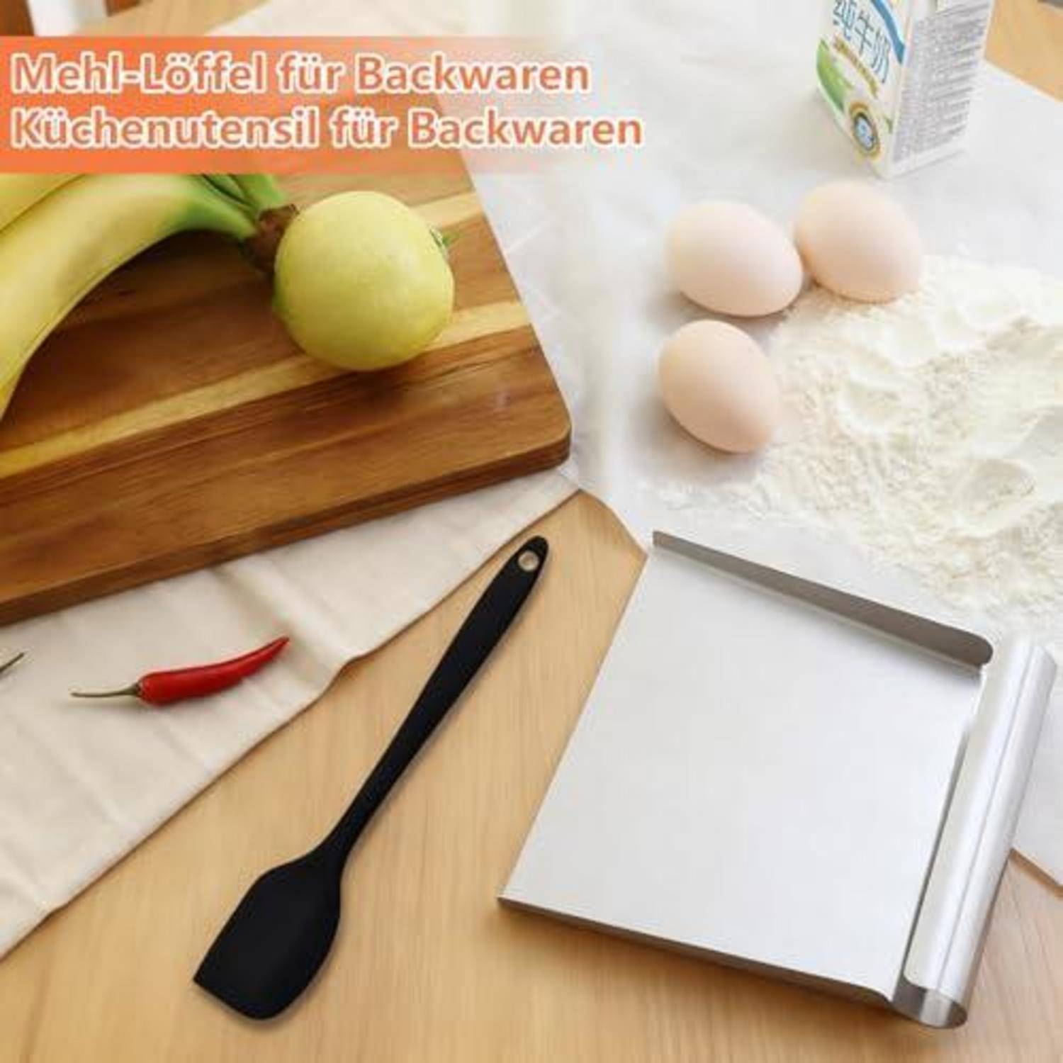 Schwarzer Backspatel auf einem Schneidebrett neben Bananen, Apfel, Eiern, Mehl und einem Backblech; deutscher Text lautet „Mehl-Löffel für Backwaren