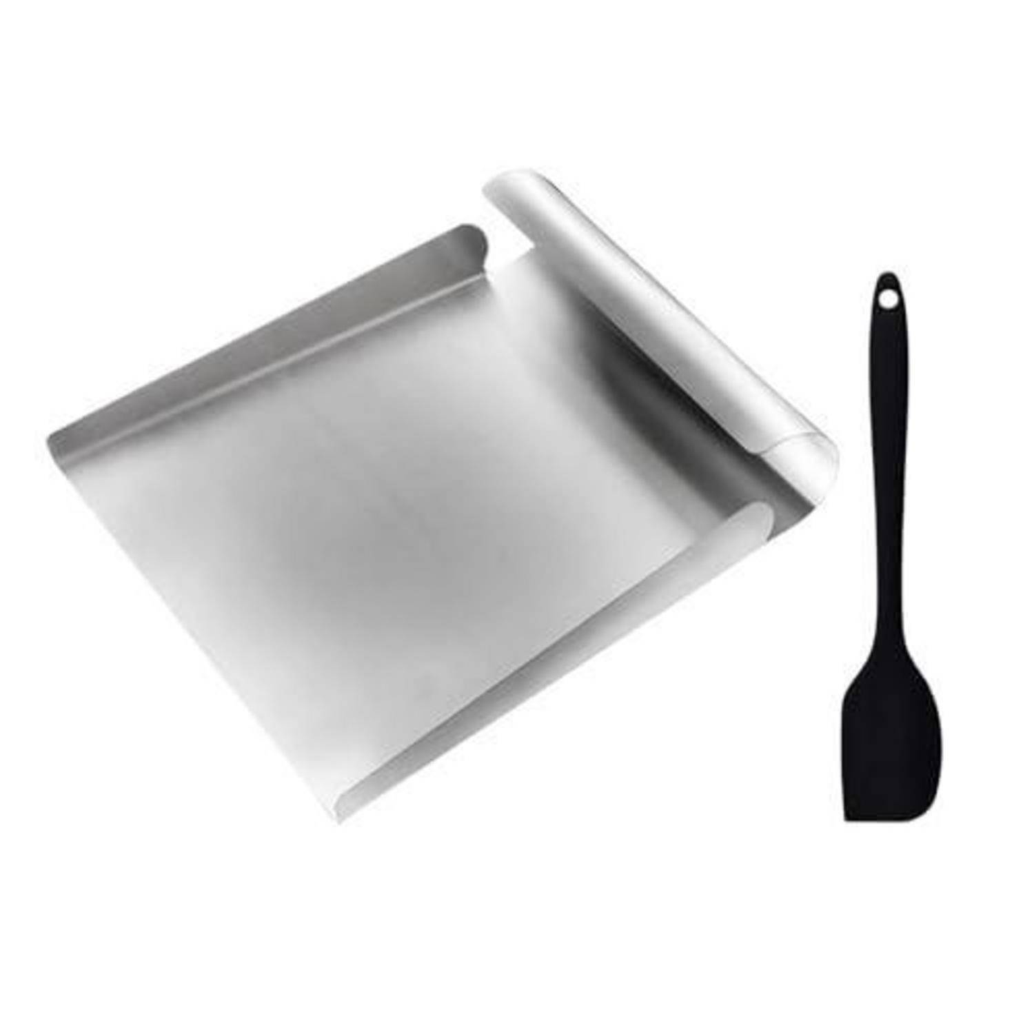 Eine quadratische Metallbackform mit umgebördelten Kanten neben einem schwarzen Silikonspatel auf weißem Hintergrund.