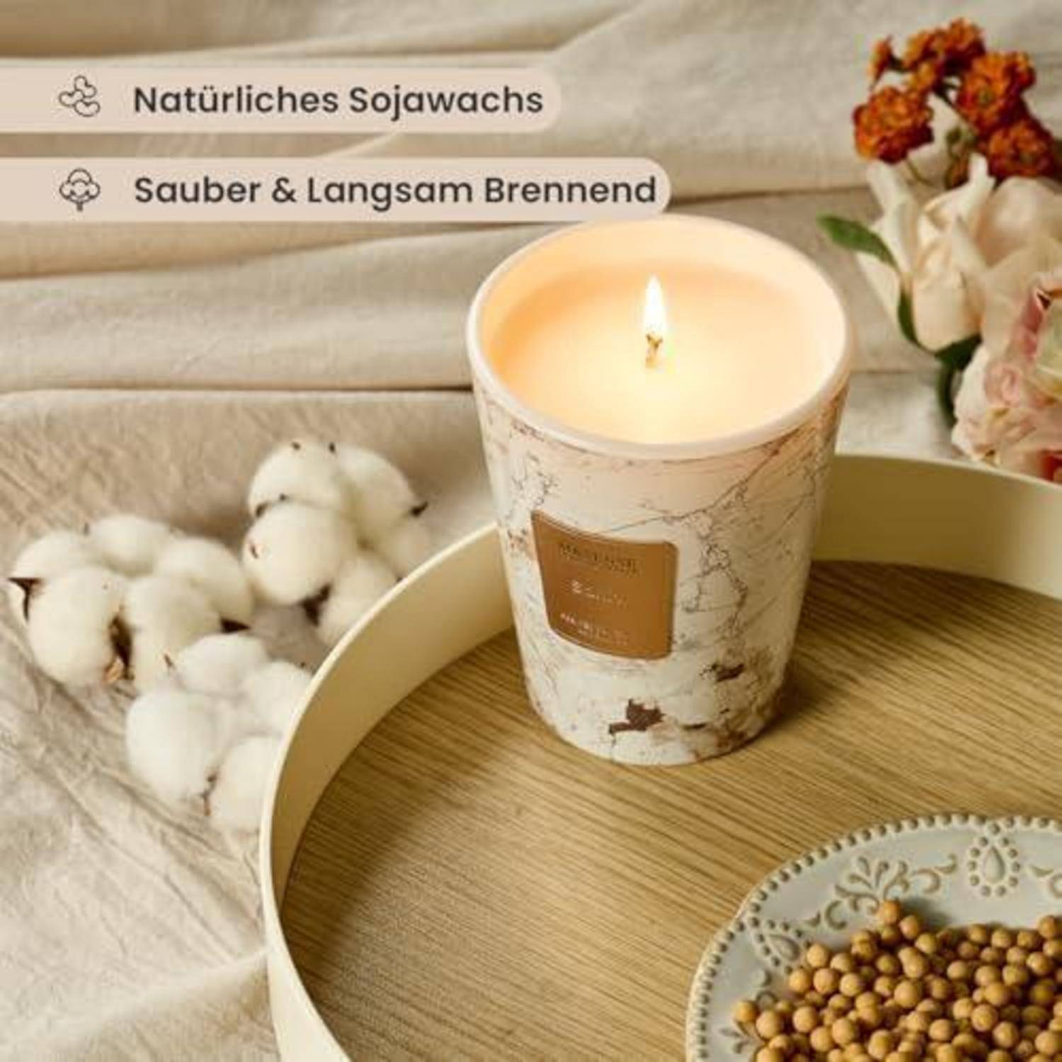 Brennende Kerze in einem dekorativen Becher mit Marmormuster auf einem Tablett mit Baumwolle und Blumen; Text liest „Natürliches Sojawachs" und „Sauber & Langsam Brennend"".