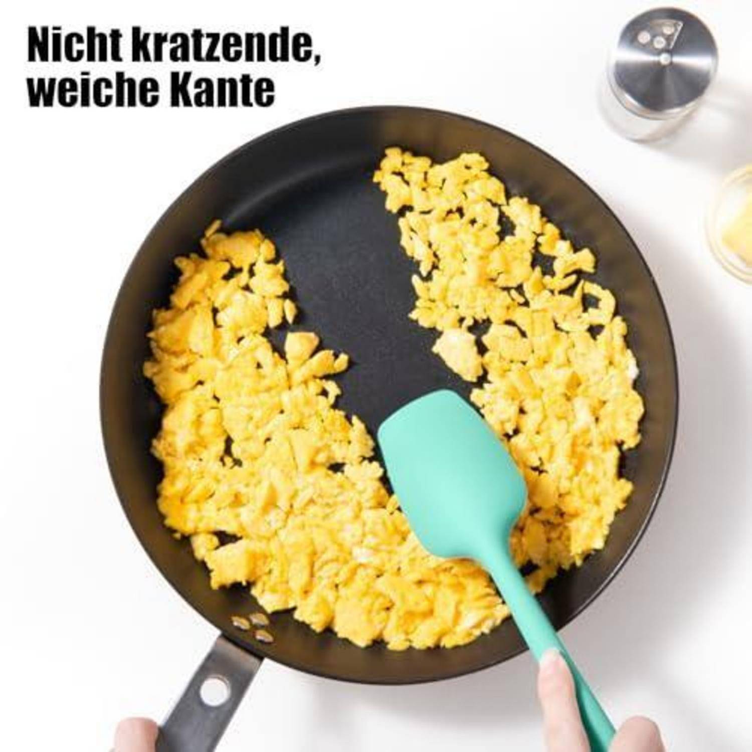 Ein Pfannenspatula mit gerührten Eiern, die mit einem Spatel in einer Pfanne umgerührt werden, mit dem deutschen Text „Nicht kratzende, weiche Kante