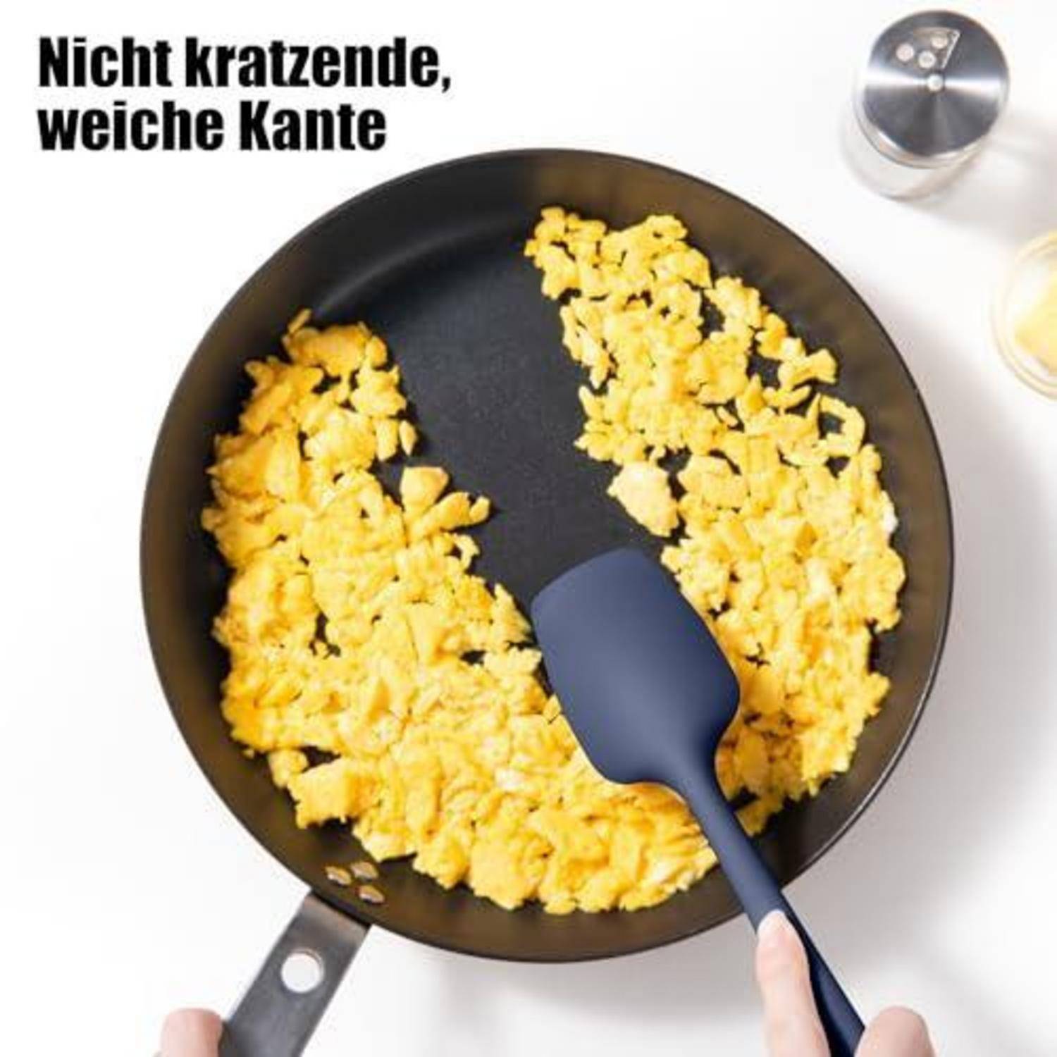 Luftaufnahme von in einer Antihaft-Pfanne zubereiteten Rühreiern mit einem Spatel, der die Lebensmittelfreisetzung zeigt; der Text besagt „Nicht kratzende, weiche Kante