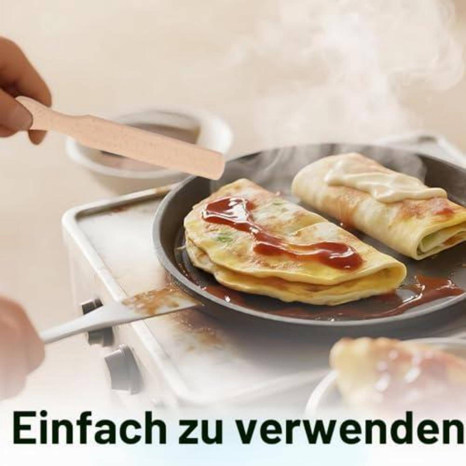 Hand fügt Teig in eine dampfende Pfanne mit gefalteten Crêpes oder Omeletten auf einem Herd hinzu; deutscher Text besagt „Einfach zu verwenden