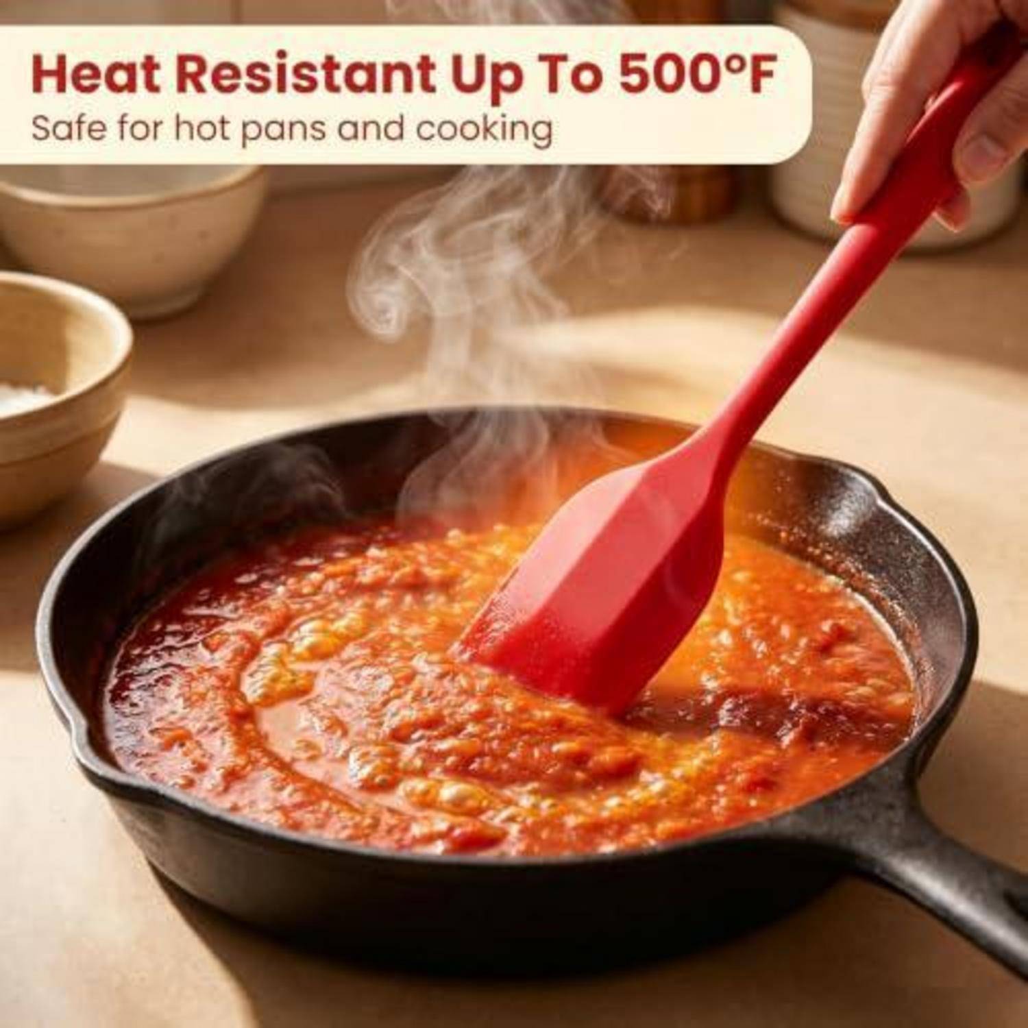 Roter Silikonspatel rührt heißes Essen in einer Gusseisenpfanne um, mit Text, der besagt „Hitzebeständig bis 500°F
