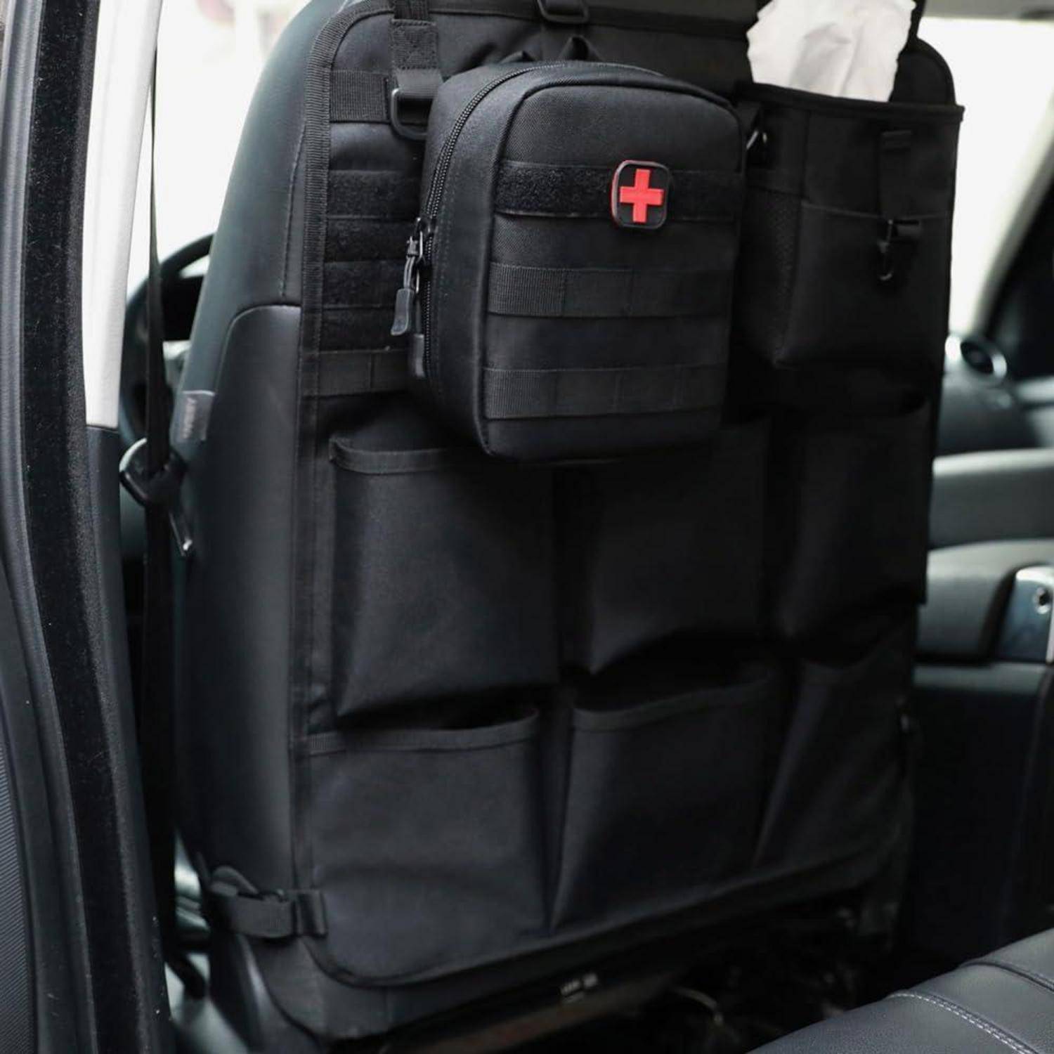 Schwarzer Autositzorganizer mit mehreren Taschen und einer kleinen Erste-Hilfe-Tasche mit rotem Kreuz an der Rückseite einer Vordersitzlehne befestigt.