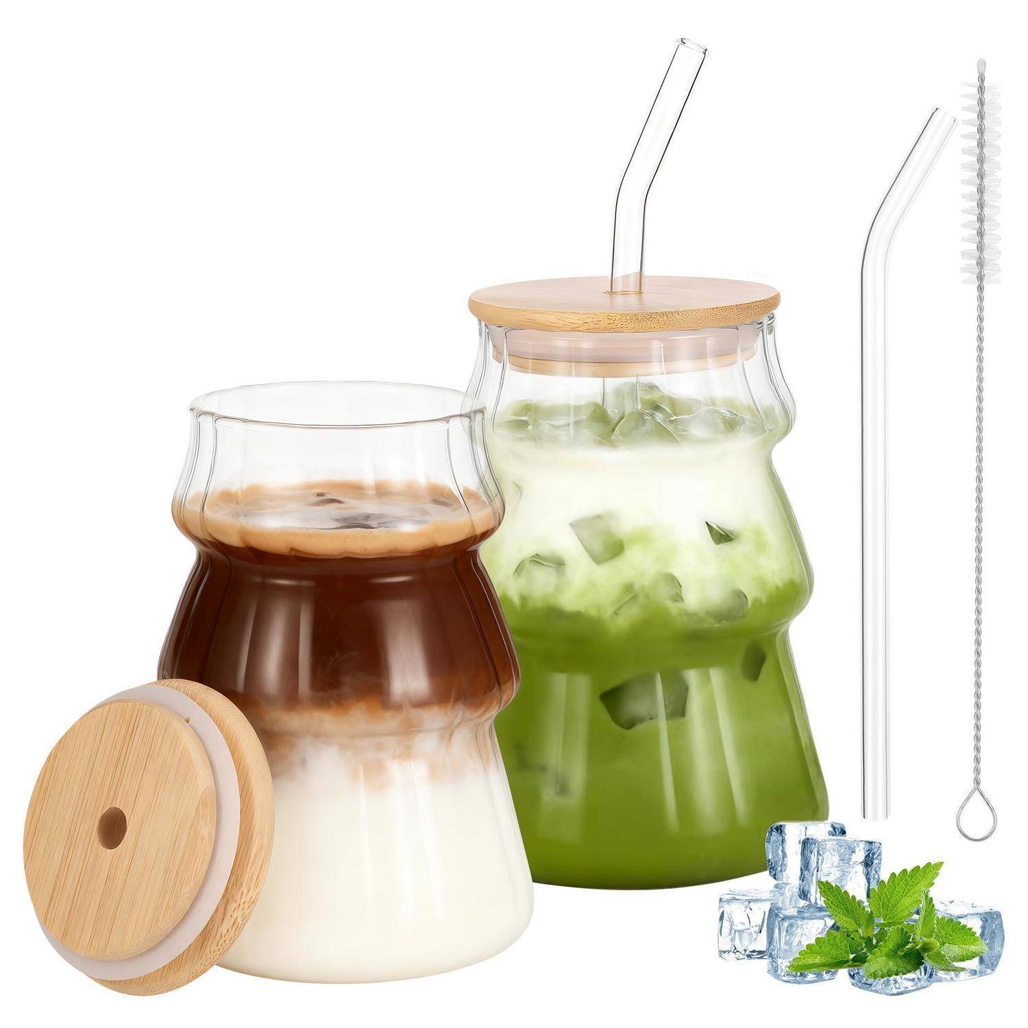 Zwei gerippte Glaskörbe mit Bambusdeckeln und Strohhalmen enthalten geschichtete eisgekühlte Getränke, eines Kaffee mit Milch und eines grüner Tee; Reinigungsbürste und Eisdekoration werden gezeigt.