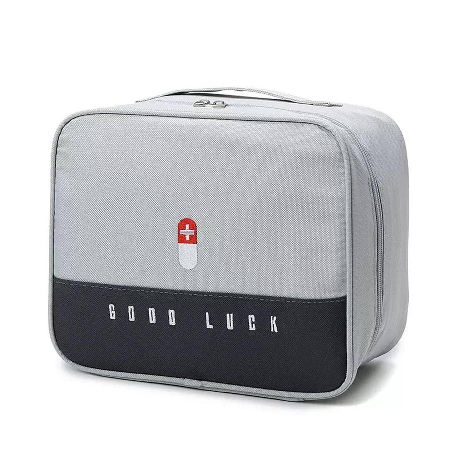 Graue quadratische Kulturtasche mit schwarzem Bodenpanel, rot-weißem Kapsel-Symbol und den Worten „GOOD LUCK