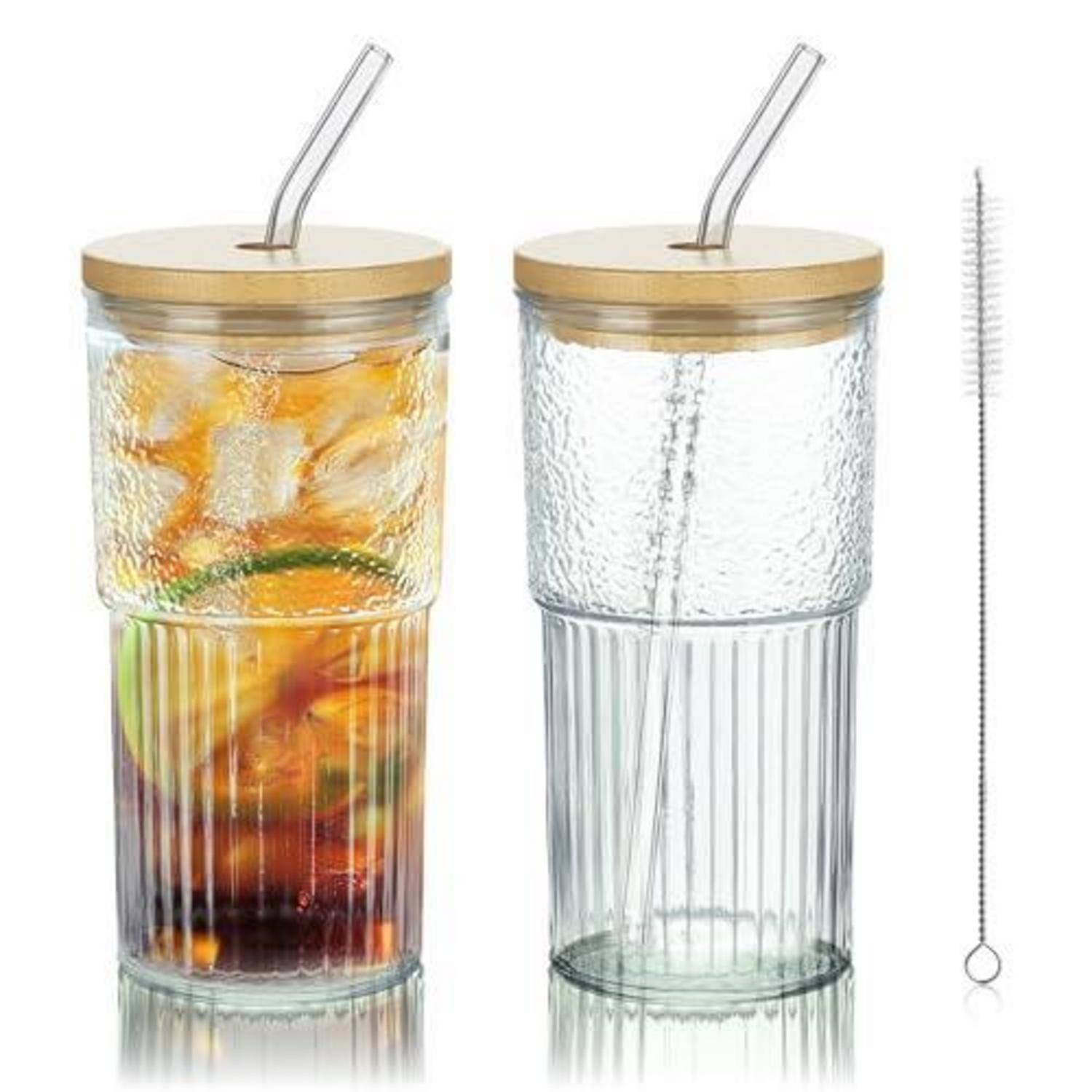 Zwei Glasbecher mit Deckel und Metallhalmen; einer enthält ein geschichtetes eisgekühltes Getränk mit Obst, der andere ist leer, daneben liegt eine Strohhalm-Reinigungsbürste.