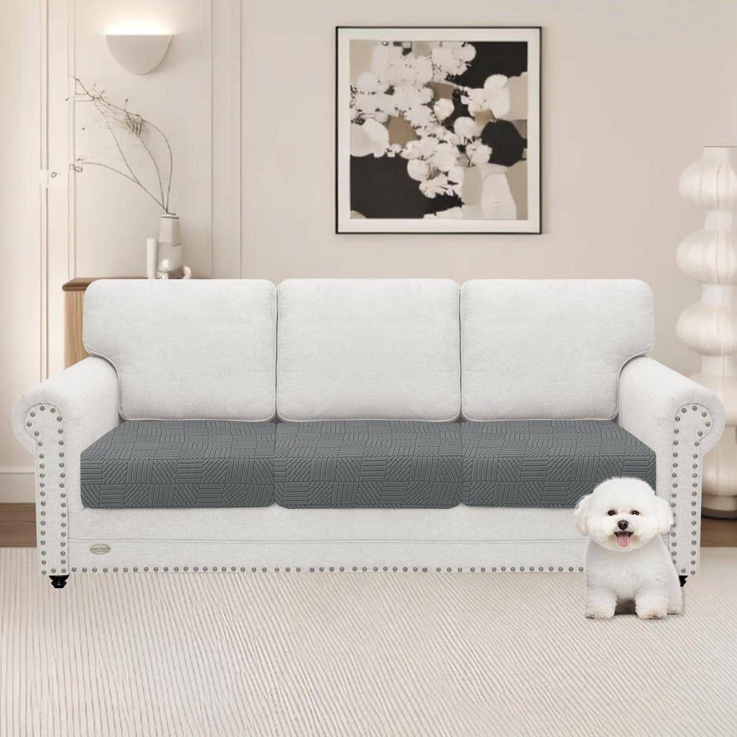 Ein weißes Sofa mit grauer Sitzbezug in einem minimalistischen Wohnzimmer, mit einem kleinen weißen Hund, der davor sitzt.