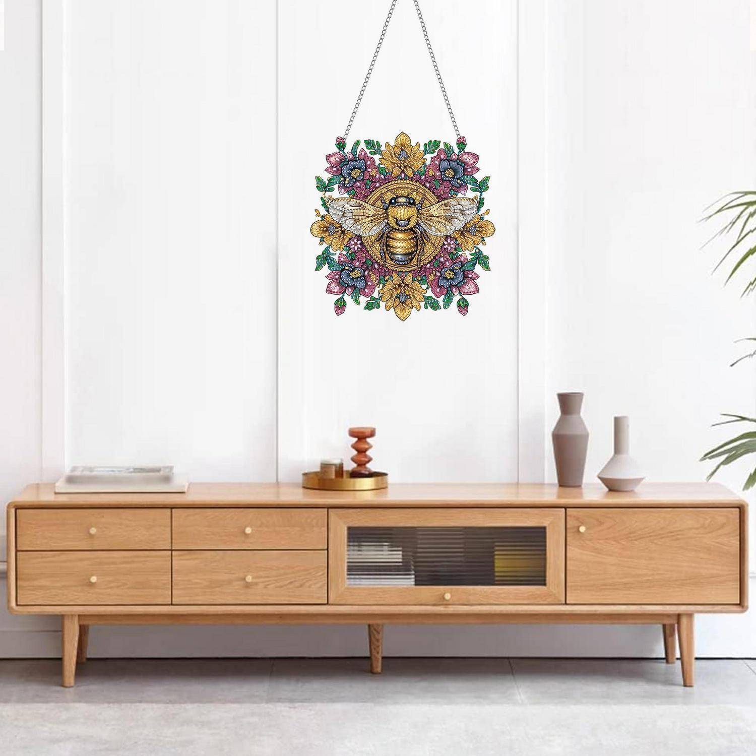 Farbenfrohe Bienen- und Blumenwandverzierung zentriert über einer hölzernen Anrichte in einem minimalistischen Zimmer.