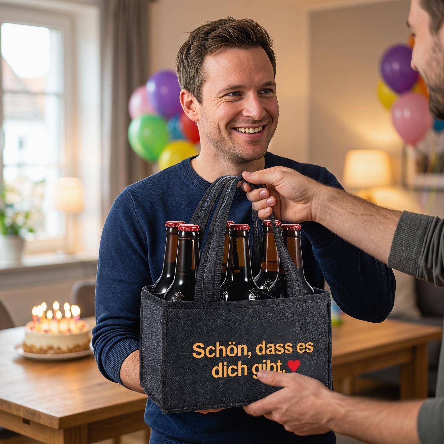 Ein Mann erhält ein Sechserpack Bier als Geschenk in einer schwarzen Tasche mit der Aufschrift „Schön, dass es dich gibt" bei einer Geburtstagsfeier mit Luftballons und Kuchen.