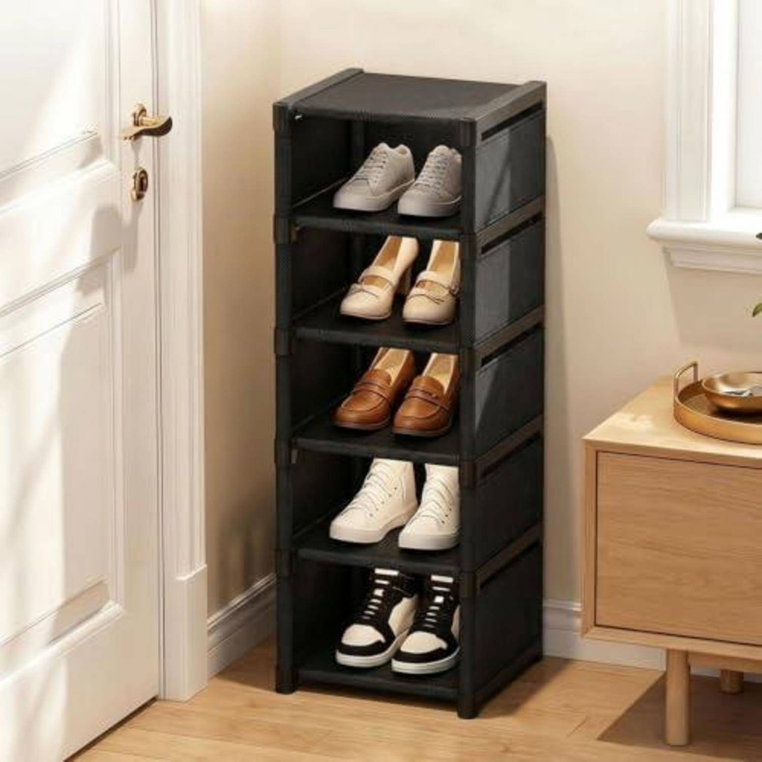 Schwarzes fünfstufiges Schuhregal mit Schuhpaaren neben einer Tür in einem aufgeräumten Zimmer.