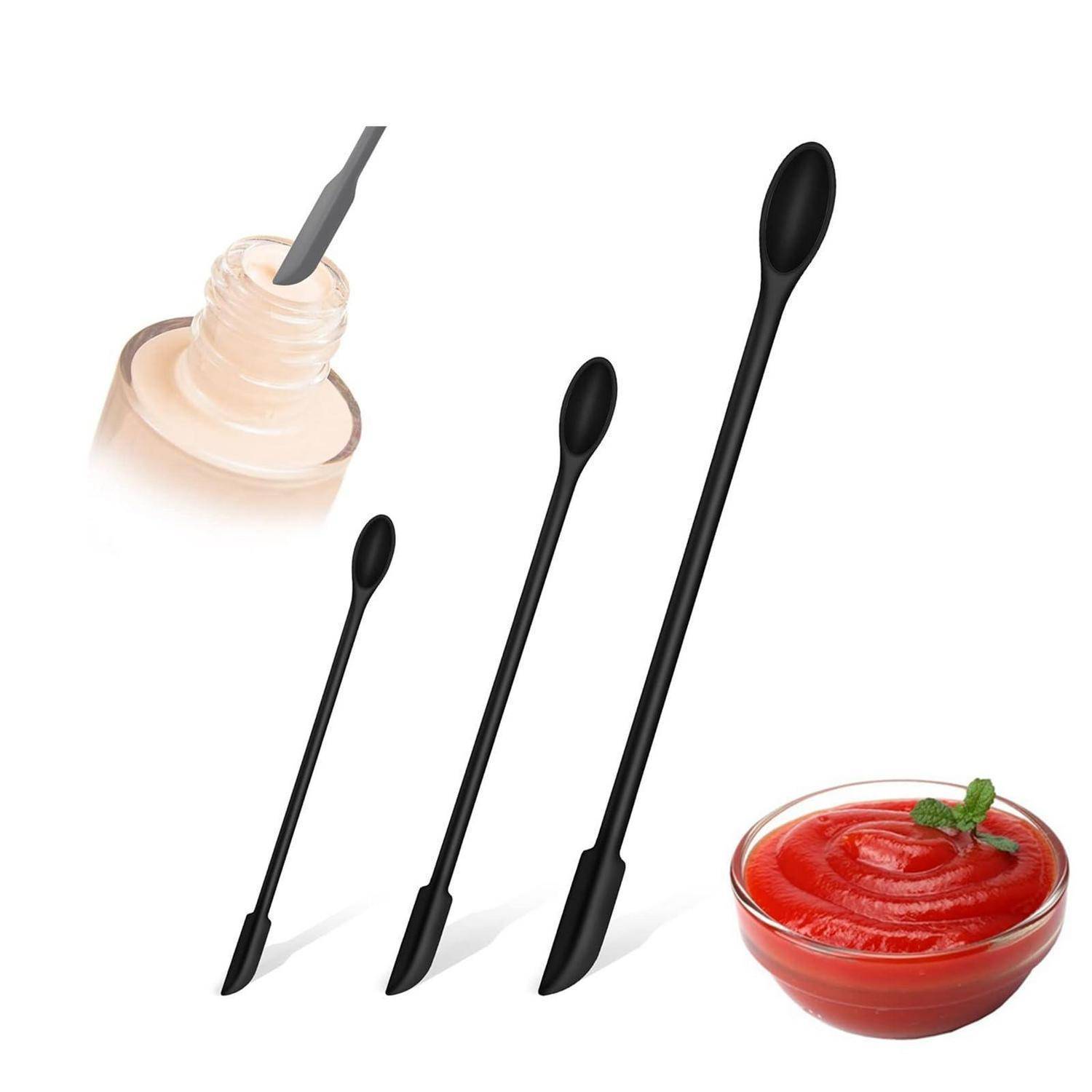 Drei schwarze Silikonspachteln verschiedener Größen zum Abkratzen von Gläsern und Mischen von Saucen, dargestellt mit einer offenen Flasche und einer Schüssel mit roter Sauce.