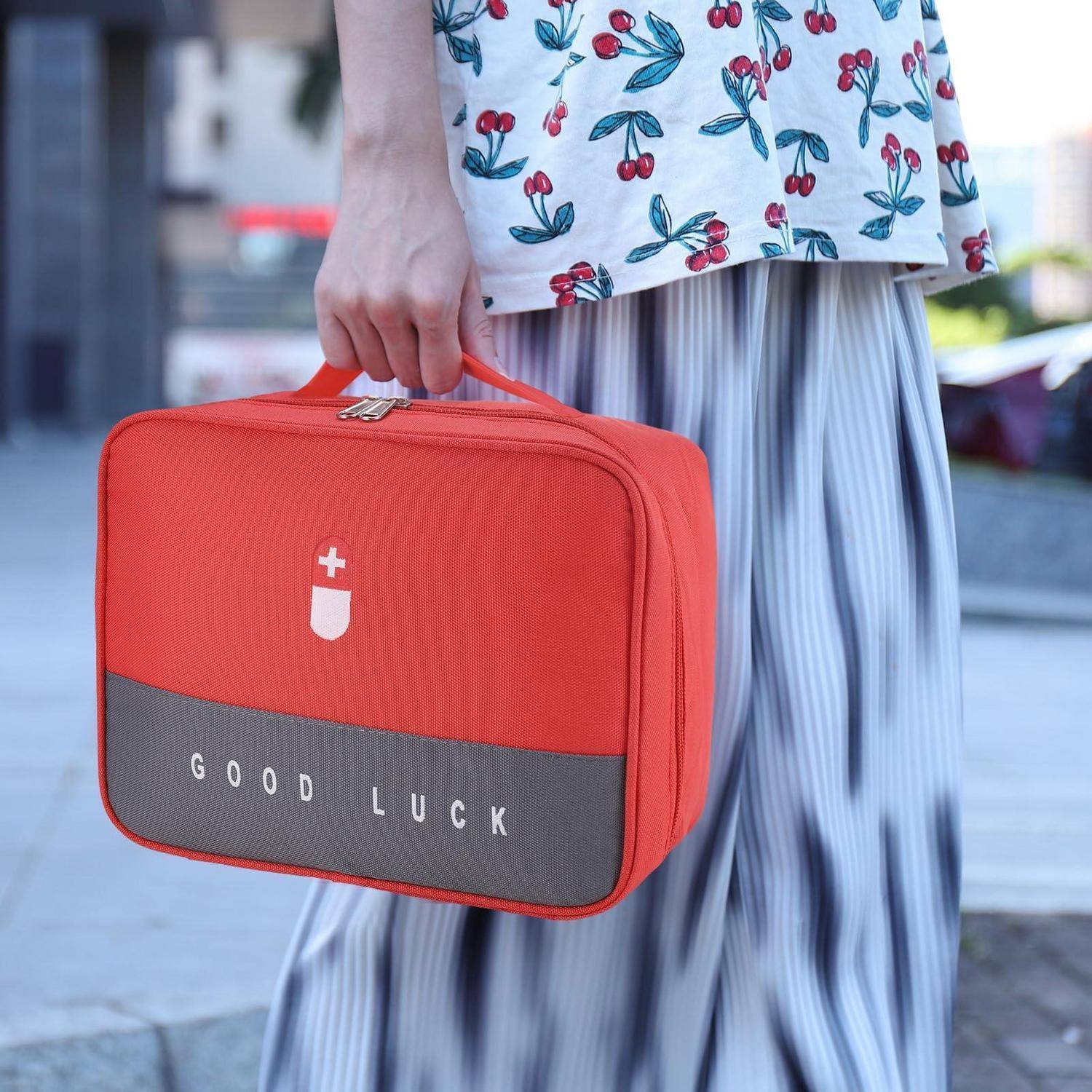 Person, die eine rote Lunchbox mit der Aufschrift „VIEL GLÜCK" hält, mit weißem Kreuzicon, während sie ein Kirschenprint-Oberteil und einen gestreiften Rock trägt.