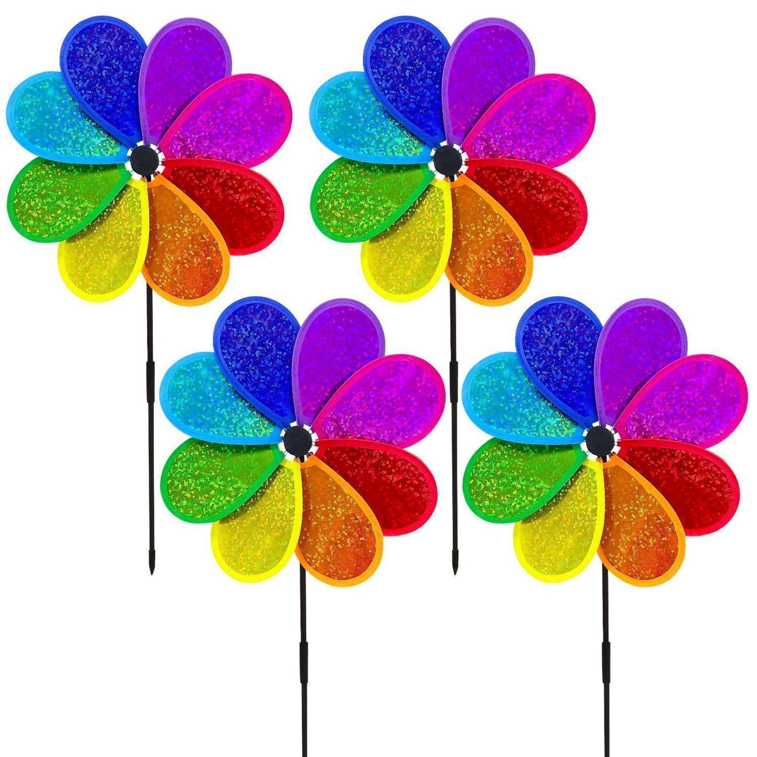 Vier regenbogenfarbige Windmühlen-Gartenstecker auf schwarzen Stielen, in einer Gruppe vor weißem Hintergrund angeordnet.