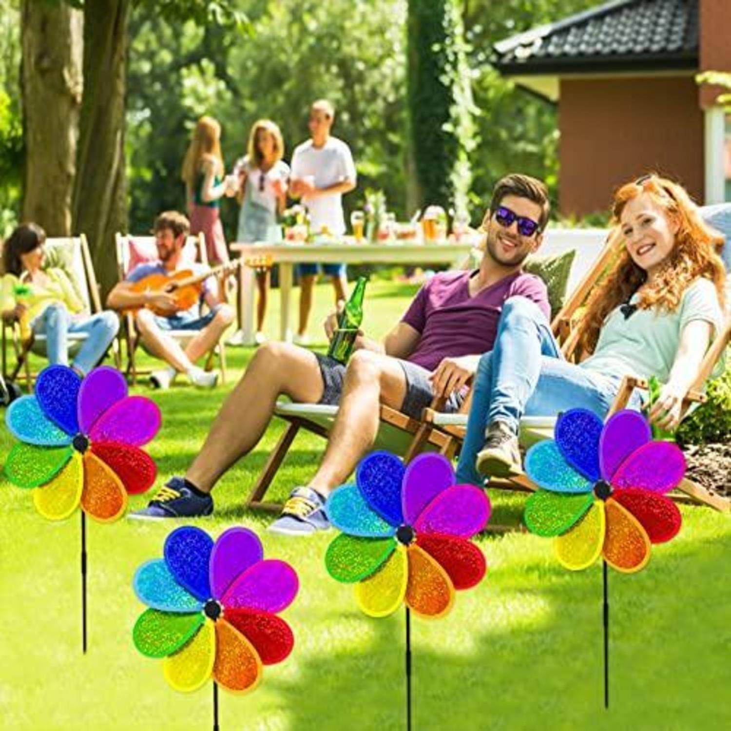 Freunde entspannen sich im Freien bei einem sonnigen Picknick im Hinterhof, mit bunten Windmühlendekorationen im Vordergrund.
