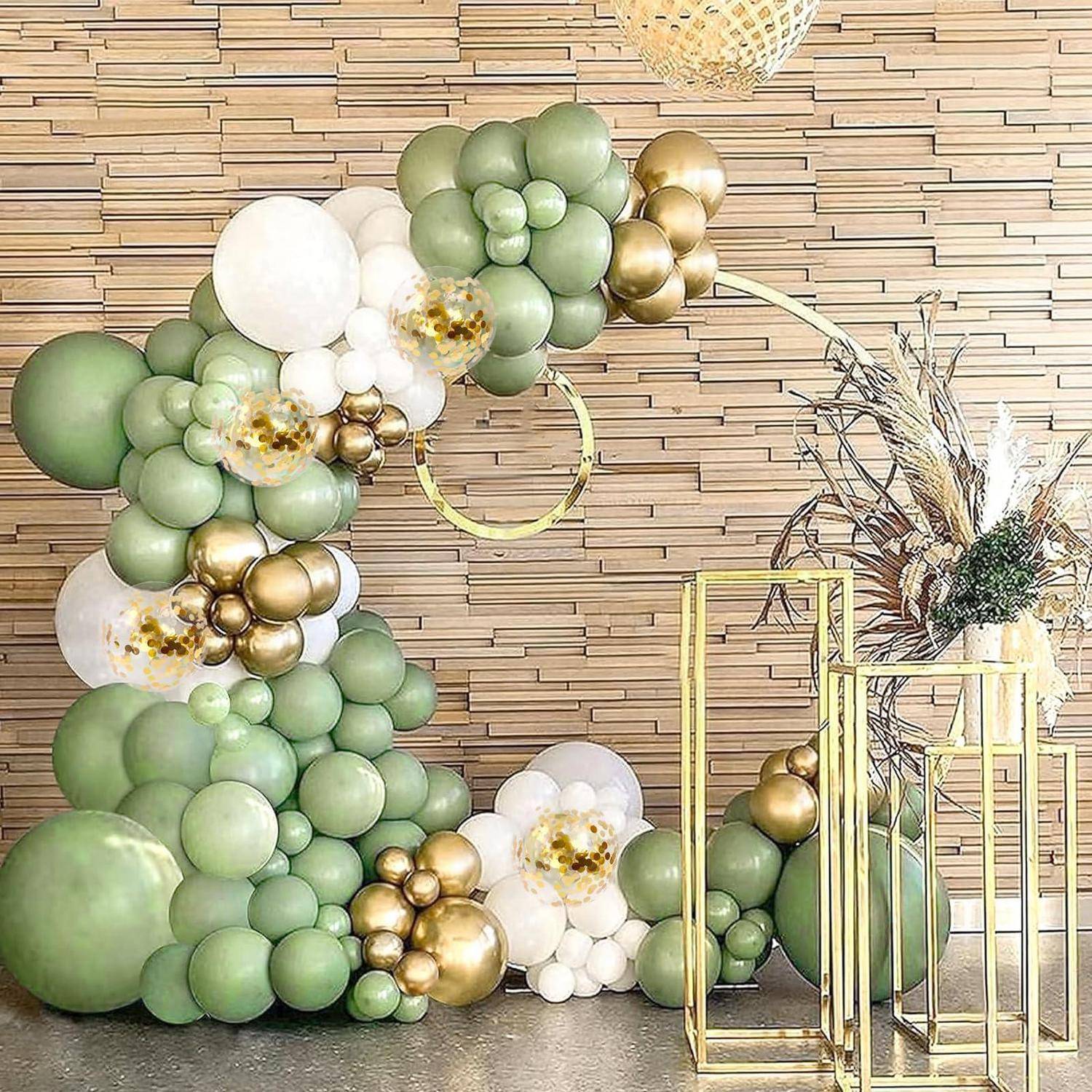 Grüne, weiße und goldene Ballongirlande, die um eine große Nummer 2 angeordnet ist, mit goldenen geometrischen Ständern und getrocknetem Blumenschmuck auf einem Holzwand-Hintergrund.