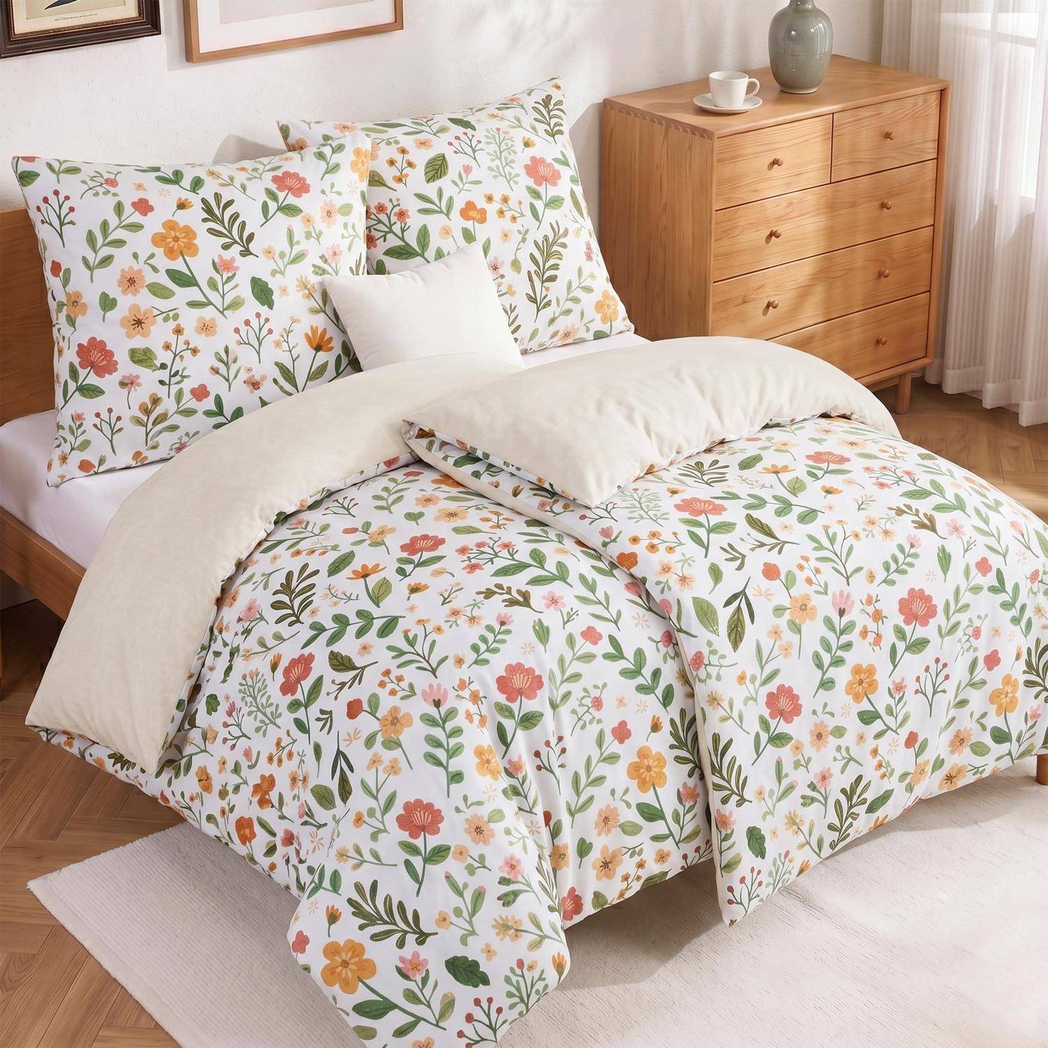 Ein ordentlich gemachtes Bett mit blumig gemustertem Bettdecken- und Kissenbezug, eine cremefarbene Wurfdecke und eine hölzerne Kommode in einem hellen Schlafzimmer.