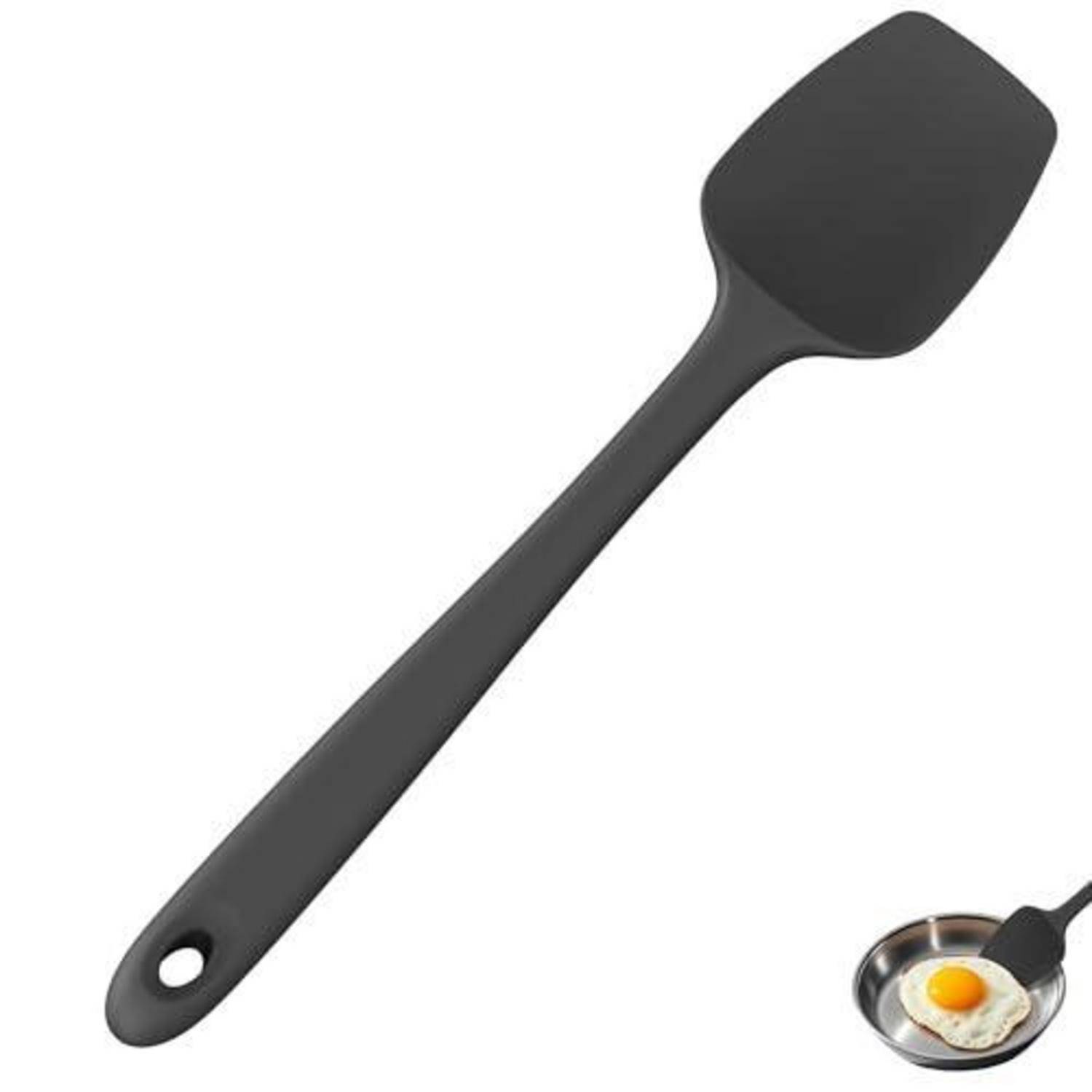 Schwarzer Silikonspachtel mit Aufhängeloch, gezeigt neben einer kleinen Pfanne mit einem Spiegelei.