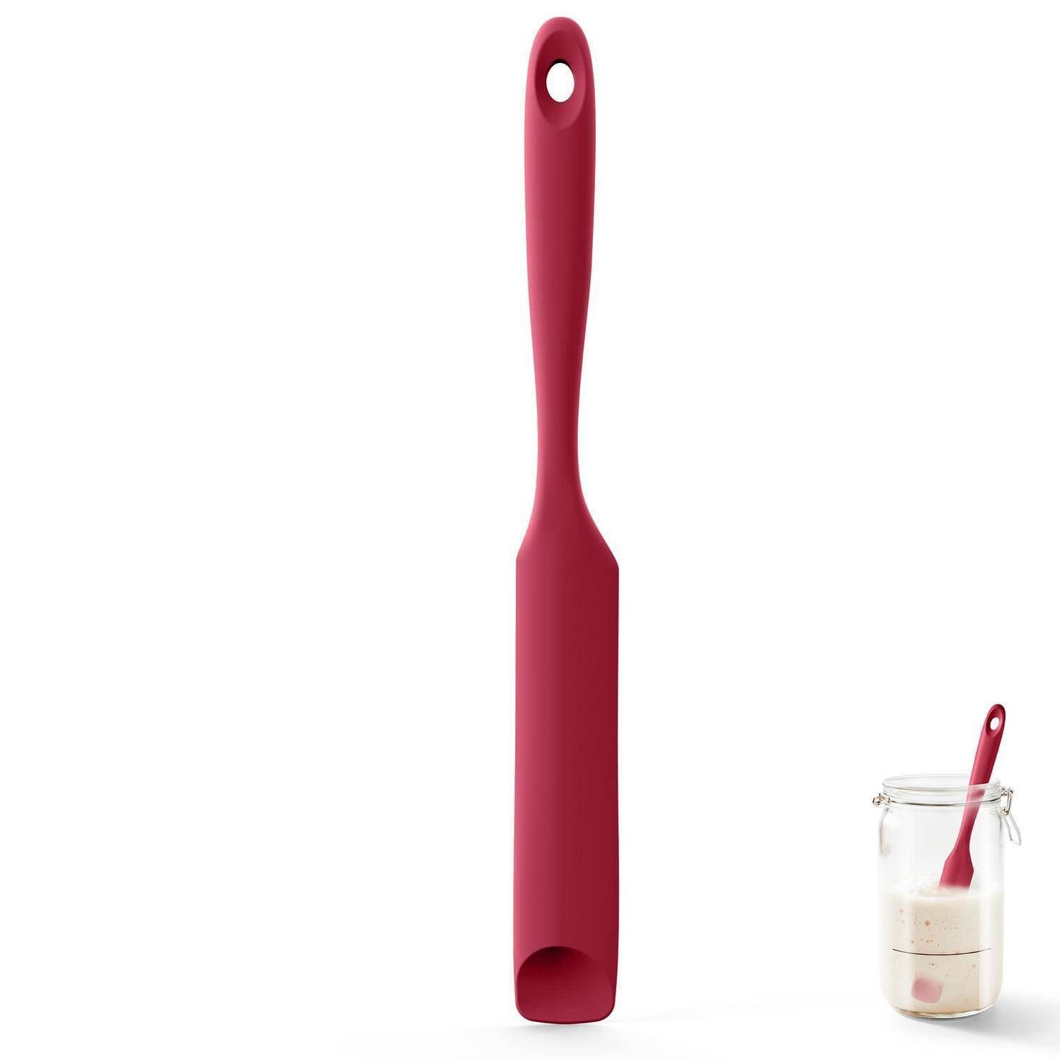 Rote Silikonspachtel mit Aufhängeloch, aufrecht auf weißem Hintergrund abgebildet; ein kleines Glas mit Teig und eine passende Spachtel befinden sich unten rechts.