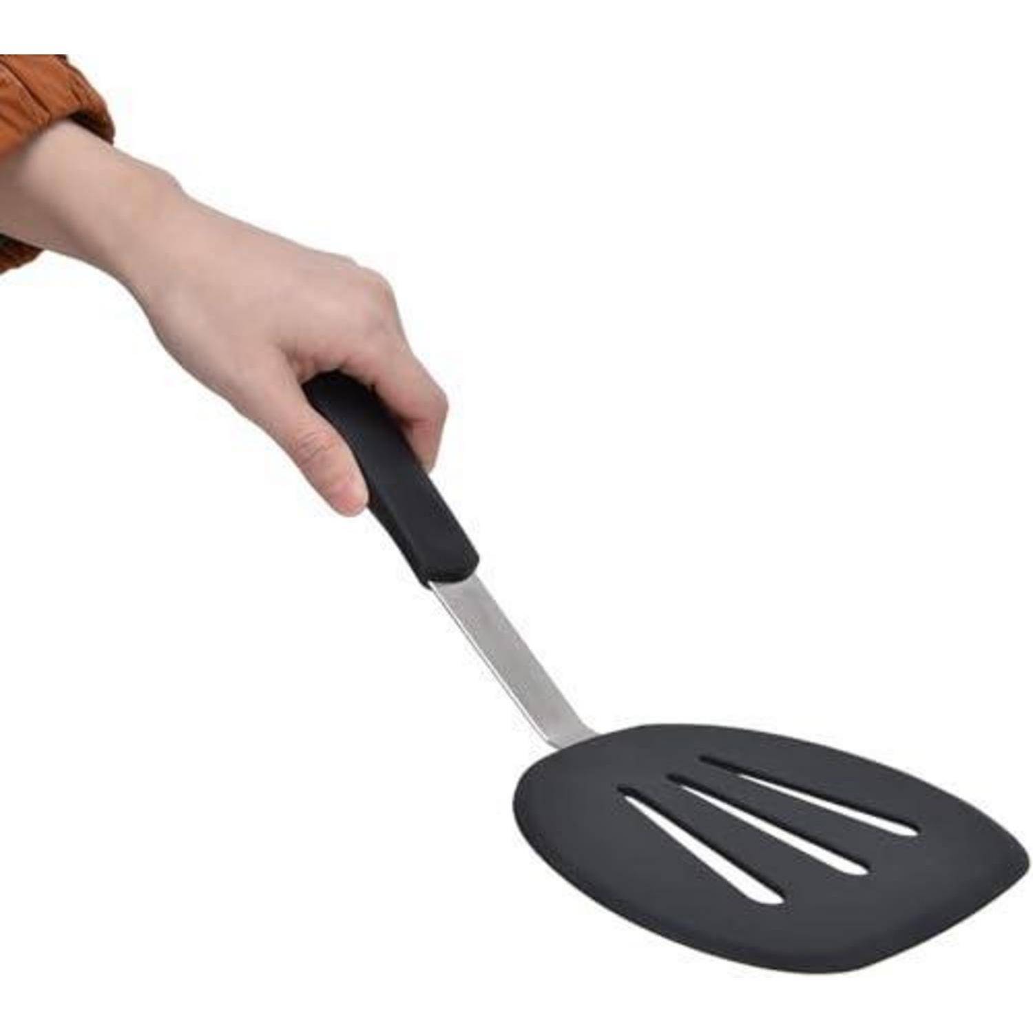 Eine Hand hält einen schwarzen Pfannenwender mit breitem, flachem Kopf auf weißem Hintergrund.