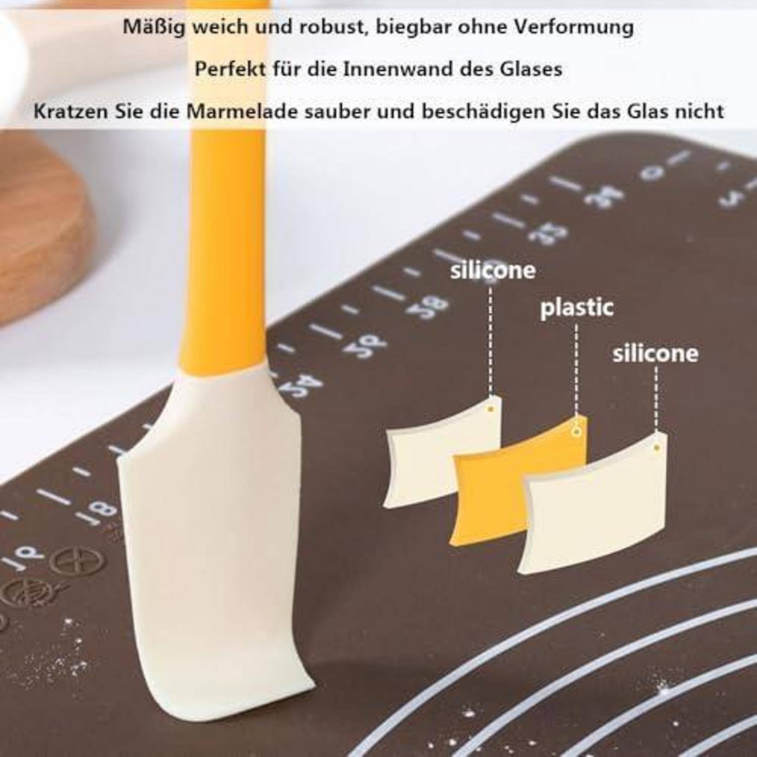Nahaufnahme eines Silikonspachtels auf einer Messmatte mit Beschriftungen zum Vergleich von Silikon und Kunststoff; deutscher Text besagt, dass er weich, langlebig und kratzt kein Glas.