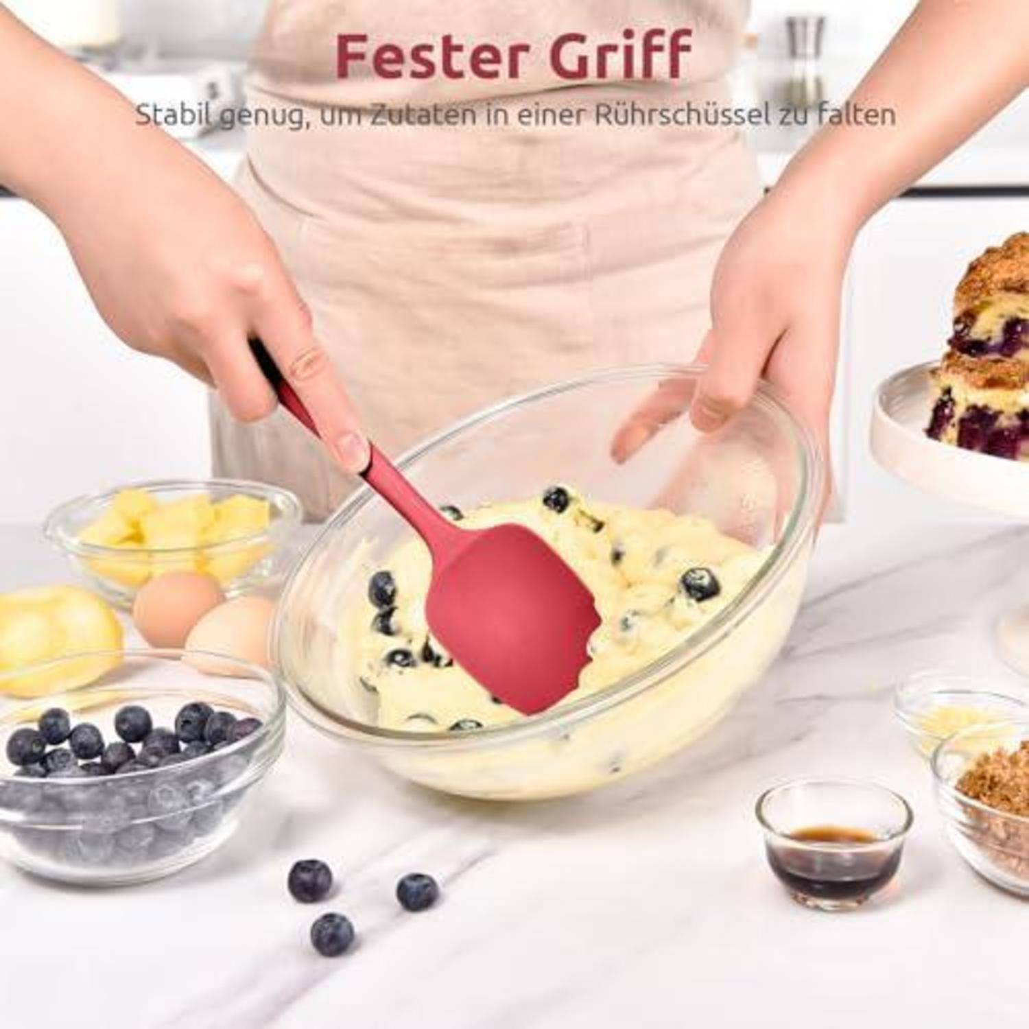 Hände falten Blaubeeren in einen Teig in einer Glasschissel; deutscher Text sagt „Ester Griff