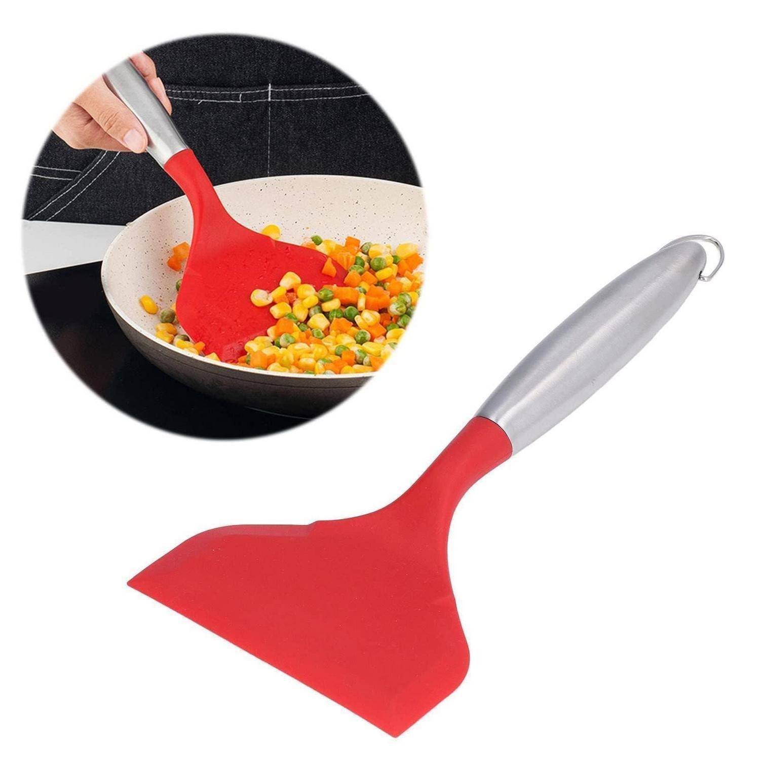 Roter Silikonkochlöffel mit silbernem Griff, wird zum Umrühren von Gemüse in einer Pfanne verwendet.