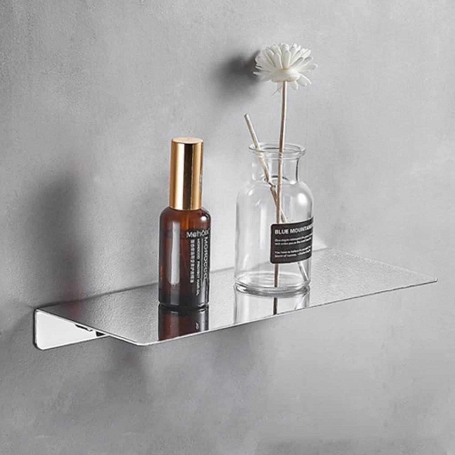 Ein an der Wand montiertes verspiegeltes Regal hält eine braune Flasche und eine Glasvase mit einer weißen Blume gegen eine graue Wand.