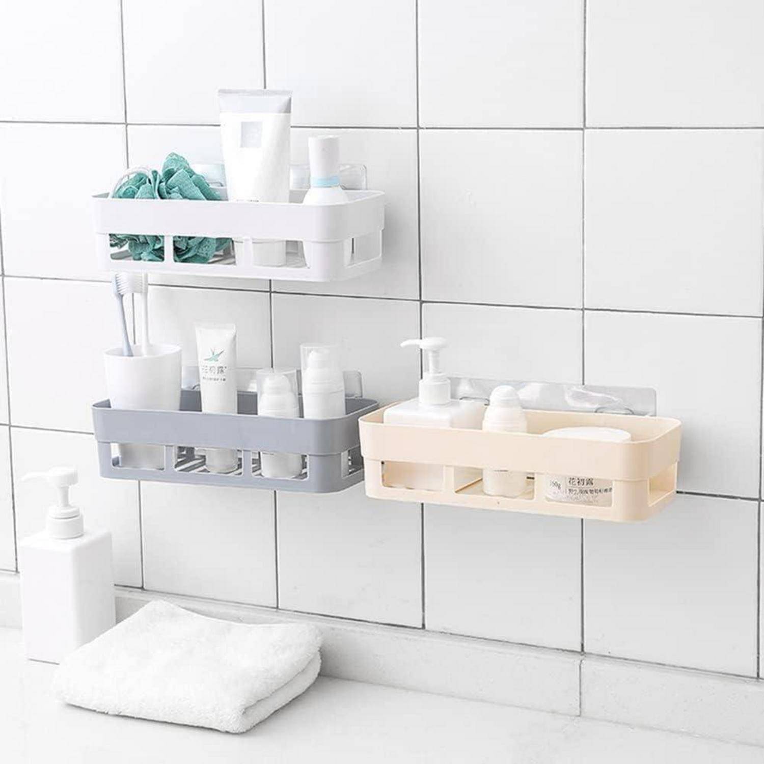 Badezimmerwandregale halten Toilettenartikel und Handtücher neben einem Waschbecken, wobei ein dreiteiliger Organizer in Weiß, Grau und Beige an einer gekachelten Wand zu sehen ist.