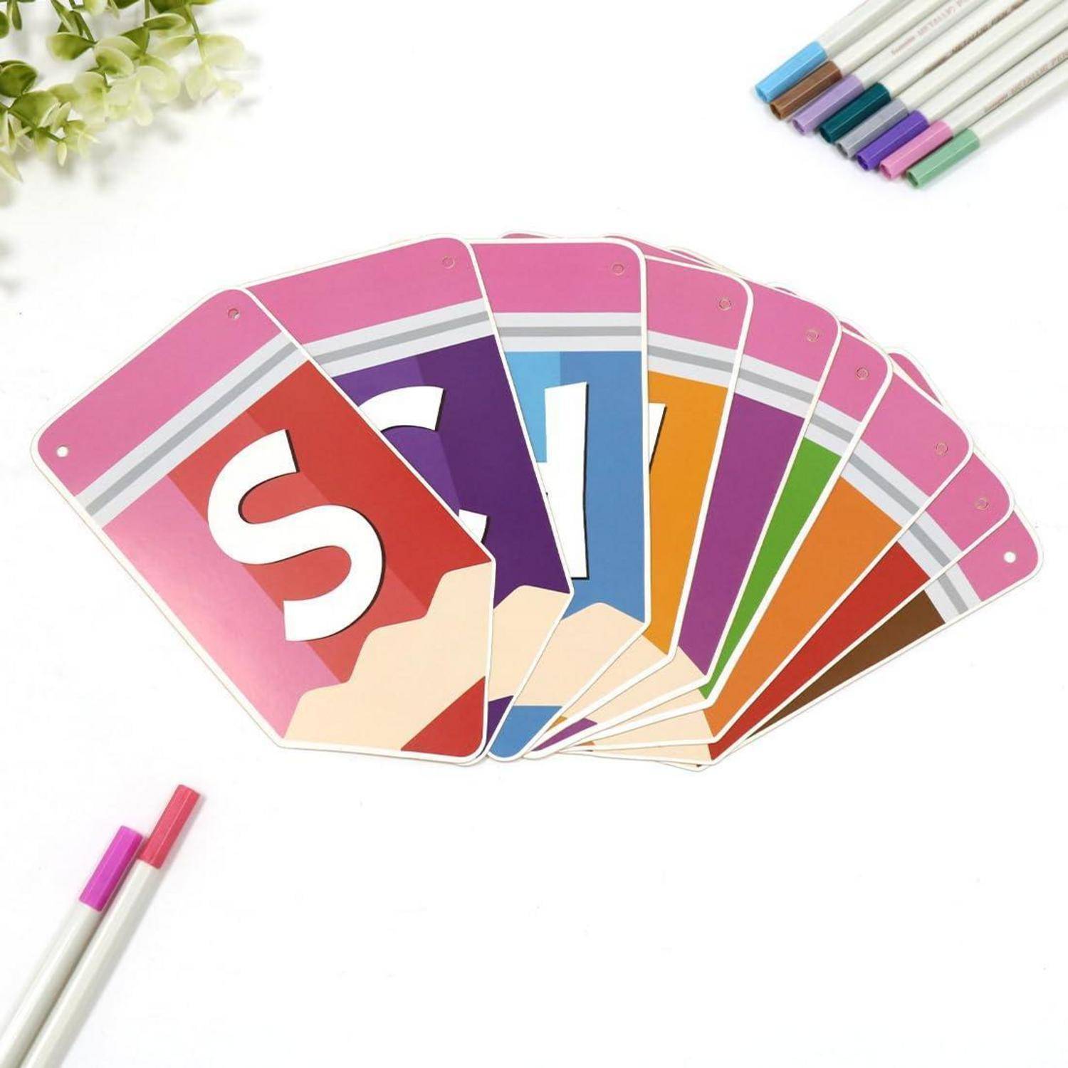 Ein Fan von bunten Alphabet-Lernkarten, die das Wort „SIGHT" auf weißem Hintergrund buchstabieren, mit Markerstiften in den Ecken.