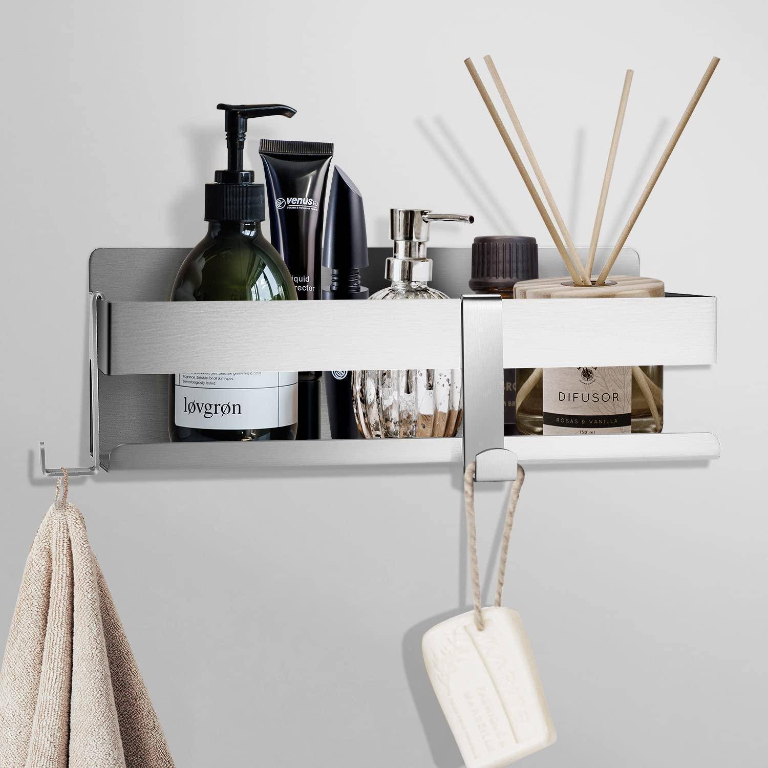 An der Wand montiertes Badezimmerregal, das Seifenspender, Lotionsflaschen und einen Raumduft mit Stäbchen hält, mit einem Handtuch und einem Badeschwamm darunter hängend.