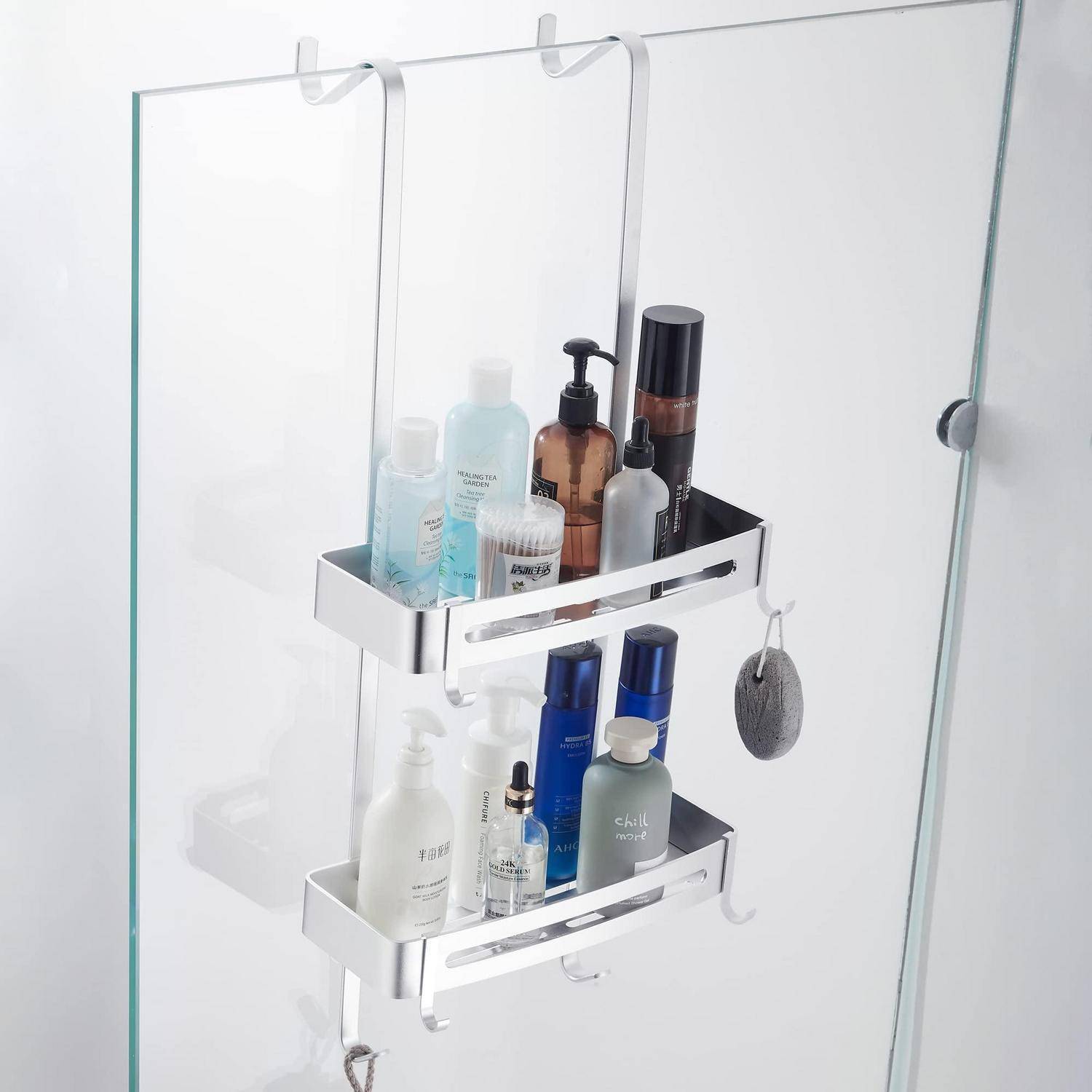 Zweistöckiger Duschkorb, der an einer gläsernen Duschtür aufgehängt ist und verschiedene Shampoo-, Seifen- und Hautpflegeflaschen sowie einen hängenden Schwamm enthält.