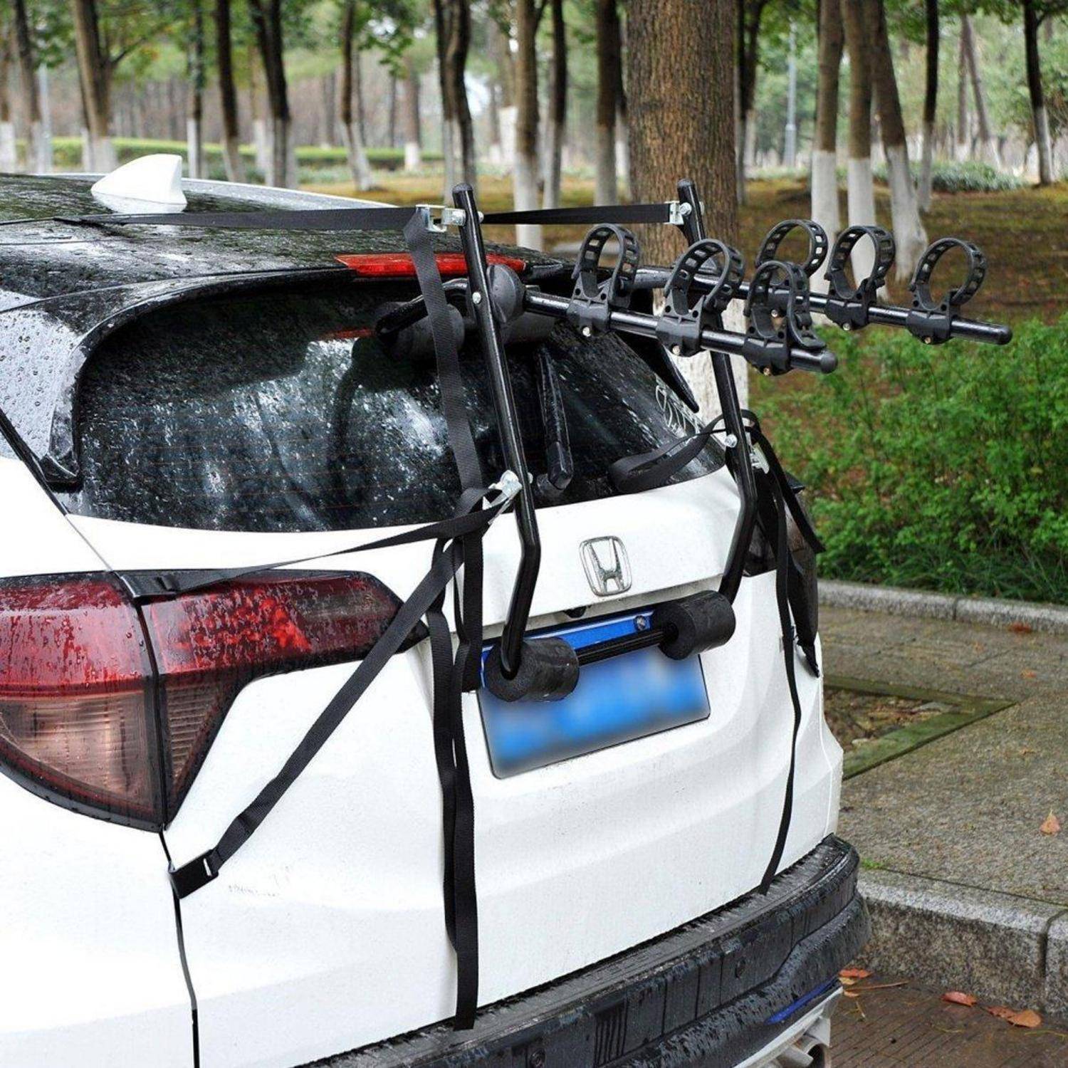 Weißer Honda SUV mit einem hinten am Heck befestigten Fahrradträger, geparkt auf einem nassen Straßenrand unter Bäumen.