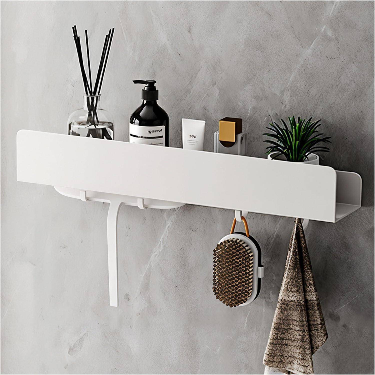 Wandmontiertes Badezimmerregal mit Toilettenartikeln, Raumduft-Diffuser, Pflanze und Bürste, mit Handtuchhaken darunter an einer grauen Wand.