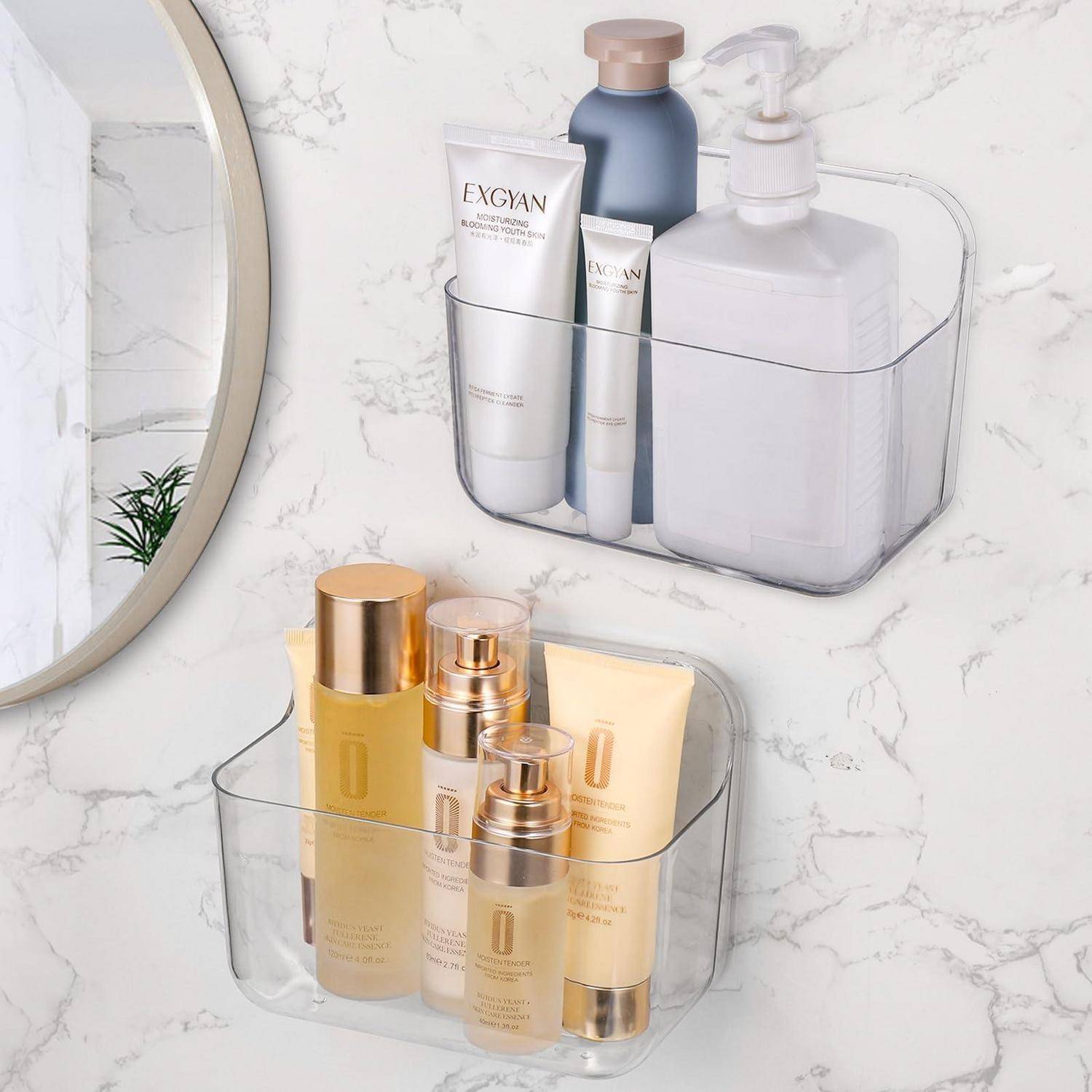 Klare, wandmontierte Badezimmerorganizer, die Hautpflege- und Toilettenflaschen und -tuben halten und eine ordentliche Lagerung an einer Wand mit Marmoroptik zeigen.
