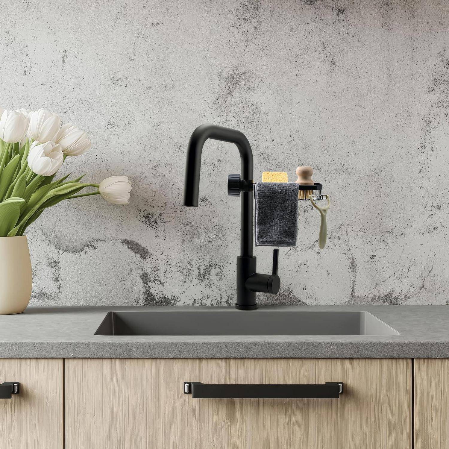 Modernes Küchenspülbecken mit schwarzem Wasserhahn, Seifenspender und Handtuchhalter, daneben eine Vase mit weißen Tulpen vor einer strukturierten grauen Wand.