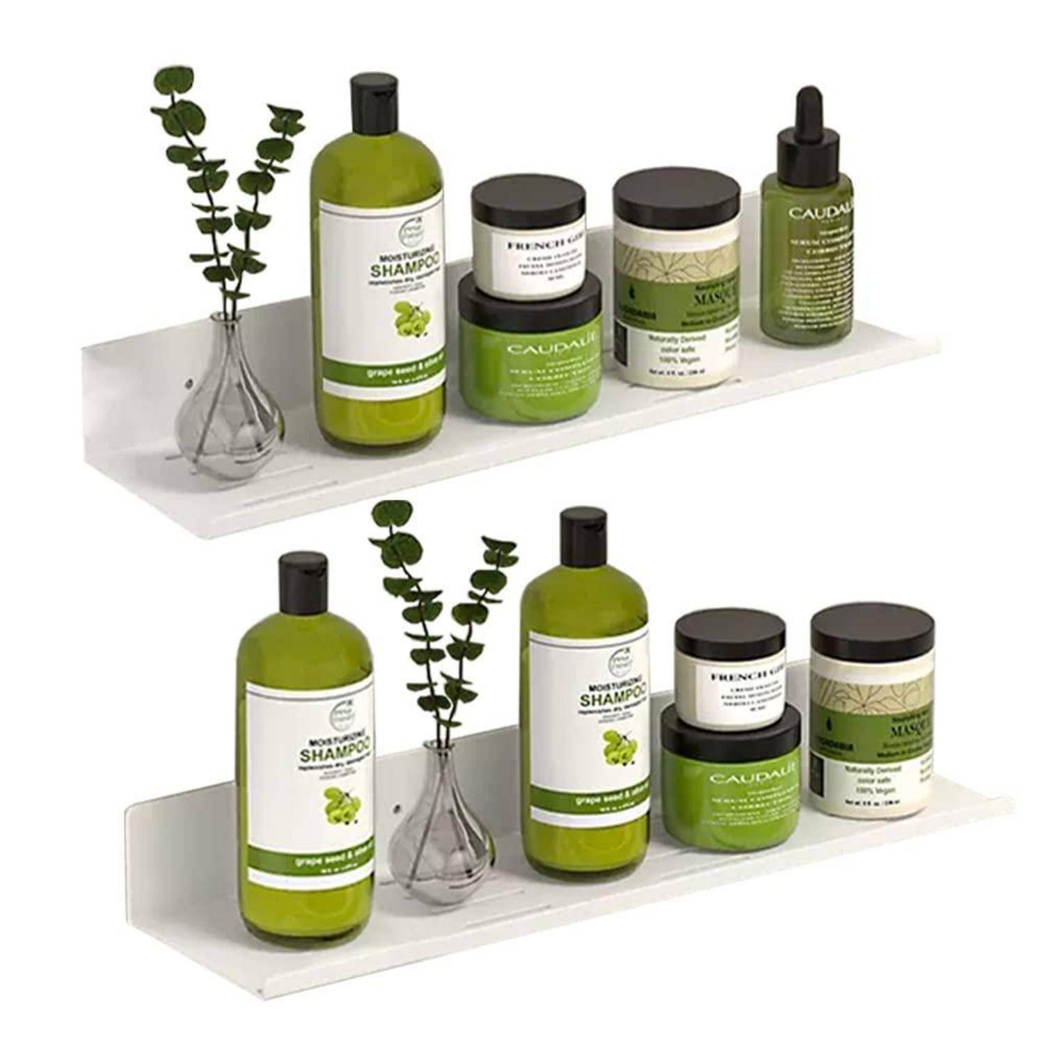 Zwei weiße Wandregale zeigen grüne Kosmetik- und Shampooflaschen mit kleinen Glasvasen und blättrigen Stängeln, arrangiert als Produktausstellung.