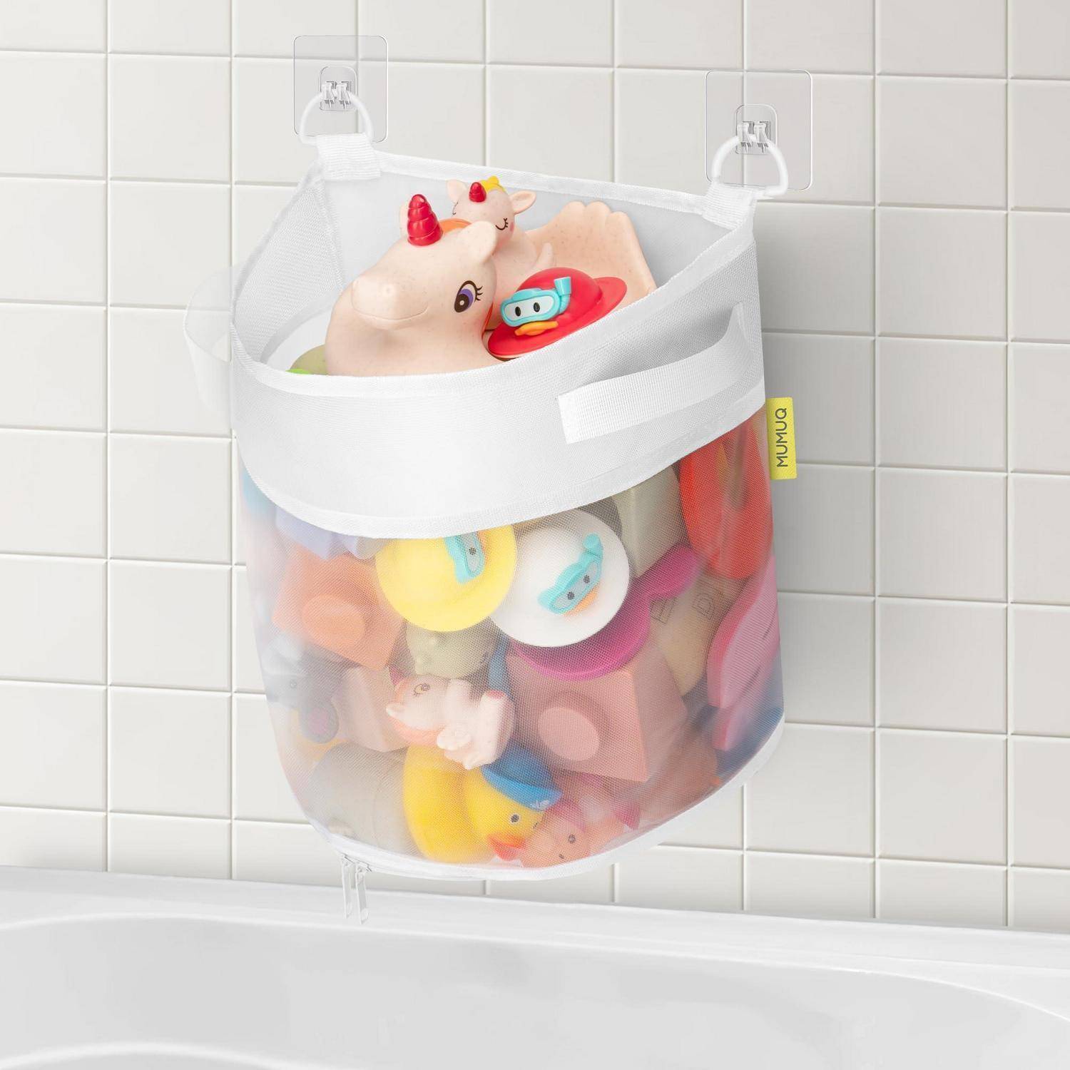 Netz-Badespielzeug-Aufbewahrungstasche, die an Badezimmerkacheln aufgehängt ist und mit bunten Kinderspielzeugen gefüllt ist und einem Einhorn-Luftmatratze obenauf.