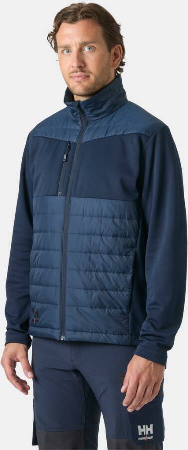Mann in einer dunkelblau gefärbten Reißverschluss-Jacke und passender Hose, stehend vor einem einfachen, hellen Hintergrund.