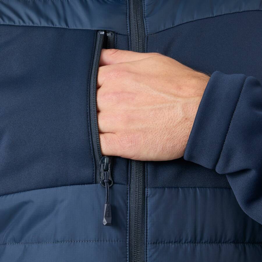 Nahaufnahme einer Hand in der Reißverschlusstasche auf der Brust einer dunkelblauenJacke.