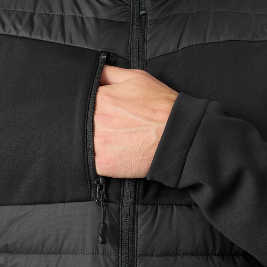 Nahaufnahme der Hand einer Person in der Brusttasche einer schwarzen Steppjacke mit Reißverschluss.