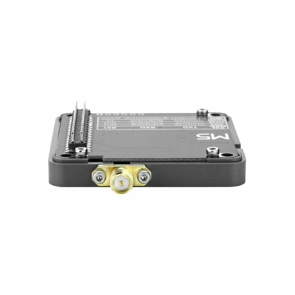 Kleines schwarzes elektronisches Modul mit einem zentralen goldfarbenen Koaxialstecker und Stiftleisten, dargestellt auf weißem Hintergrund.