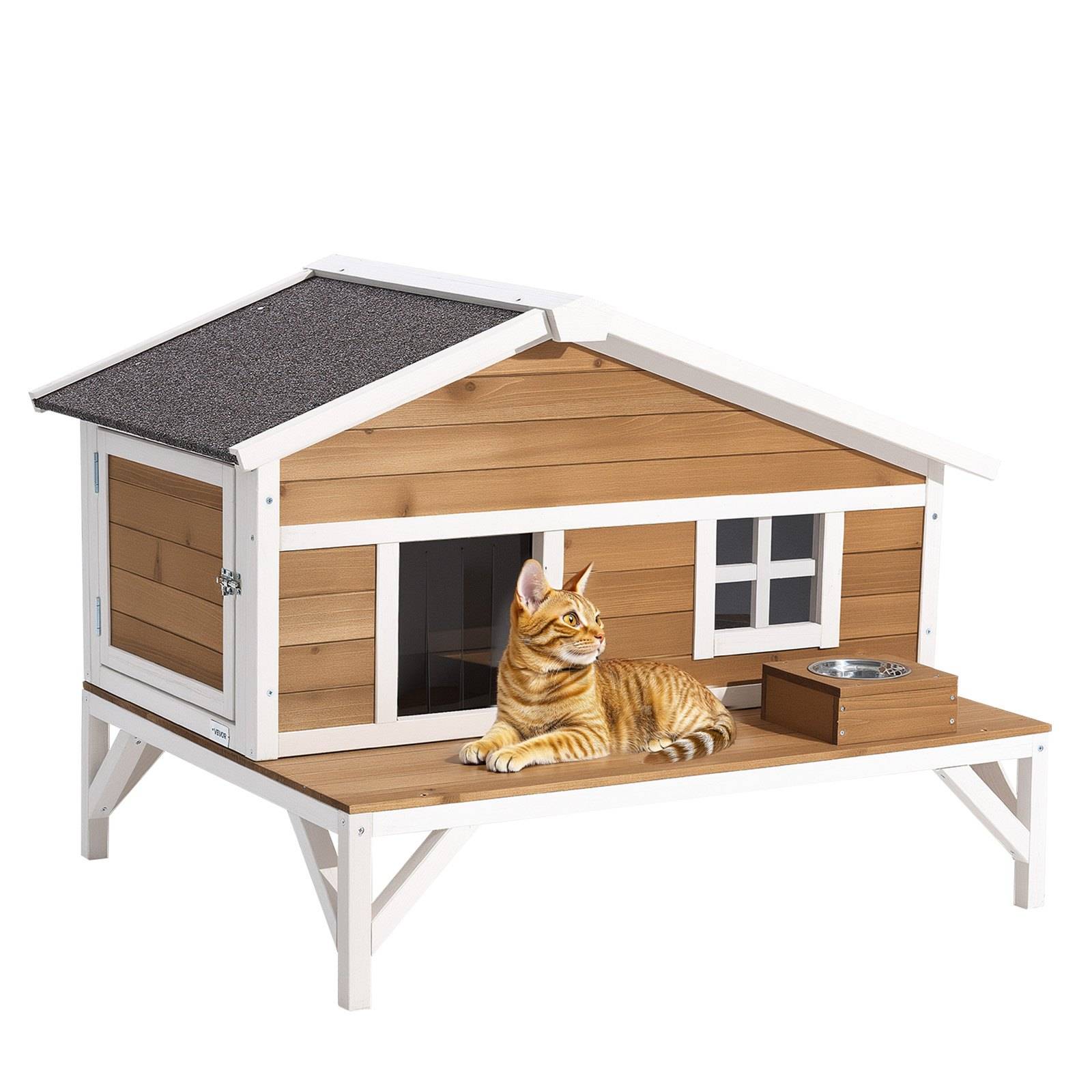 Orange getigerte Katze, die auf einem erhöhten Holz-Katzenhaus mit einer vorderen Veranda und integrierter Futternäpfen liegt, isoliert auf weißem Hintergrund.