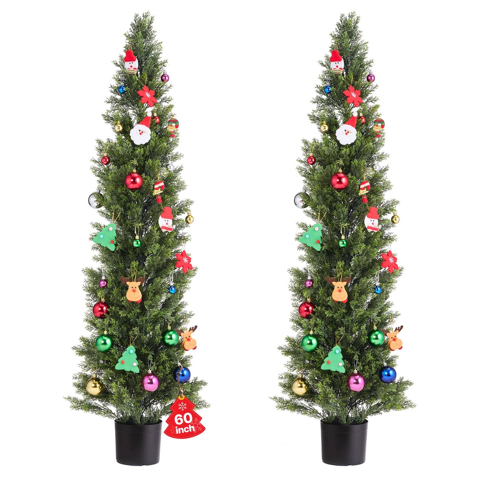Zwei schlanke künstliche Weihnachtsbäume in schwarzen Töpfen, dekoriert mit bunten Verzierungen und Weihnachtsausschnitten, nebeneinander auf weißem Hintergrund gezeigt.