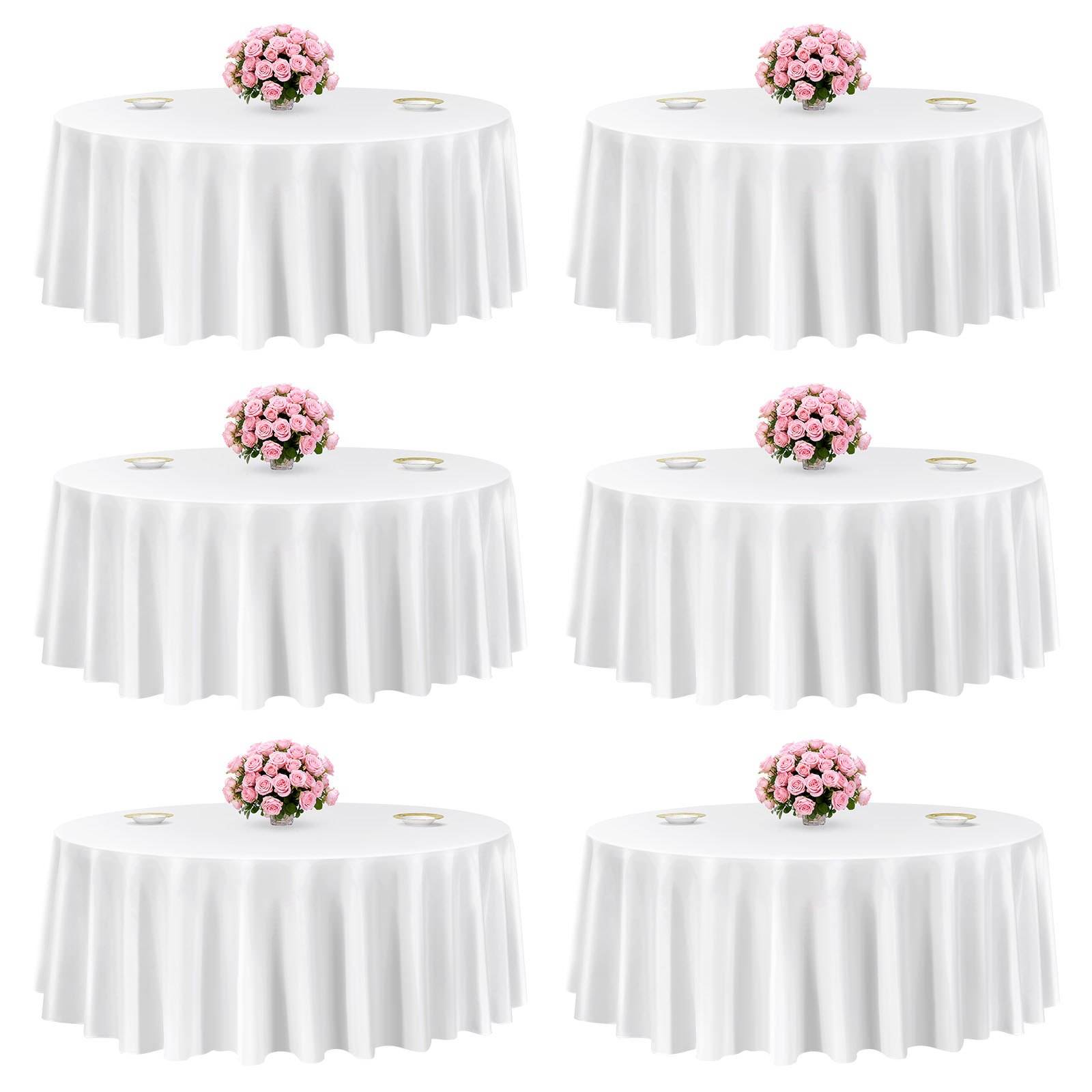 Sechs runde weiße Tische mit weißen Tischdecken, jeweils mit einem rosafarbenen Blumenmittelstück und kleinen Gedeck versehen.