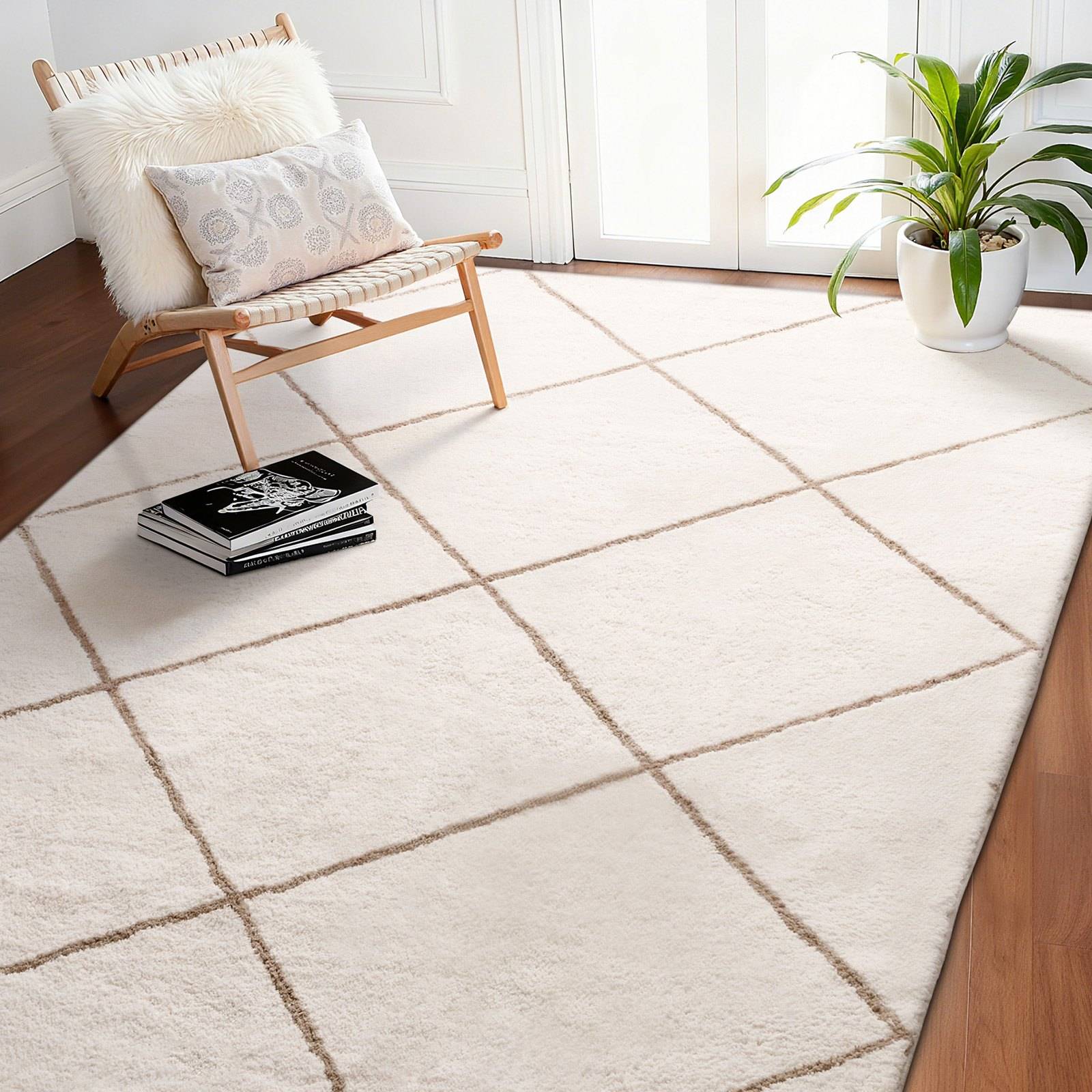 Helles Wohnzimmer mit einem cremefarbenen Teppich mit Gittermuster, einem Holz-Liegestuhl mit Kissen, einem kleinen Bücherstapel und einer Topfpflanze neben der Tür.