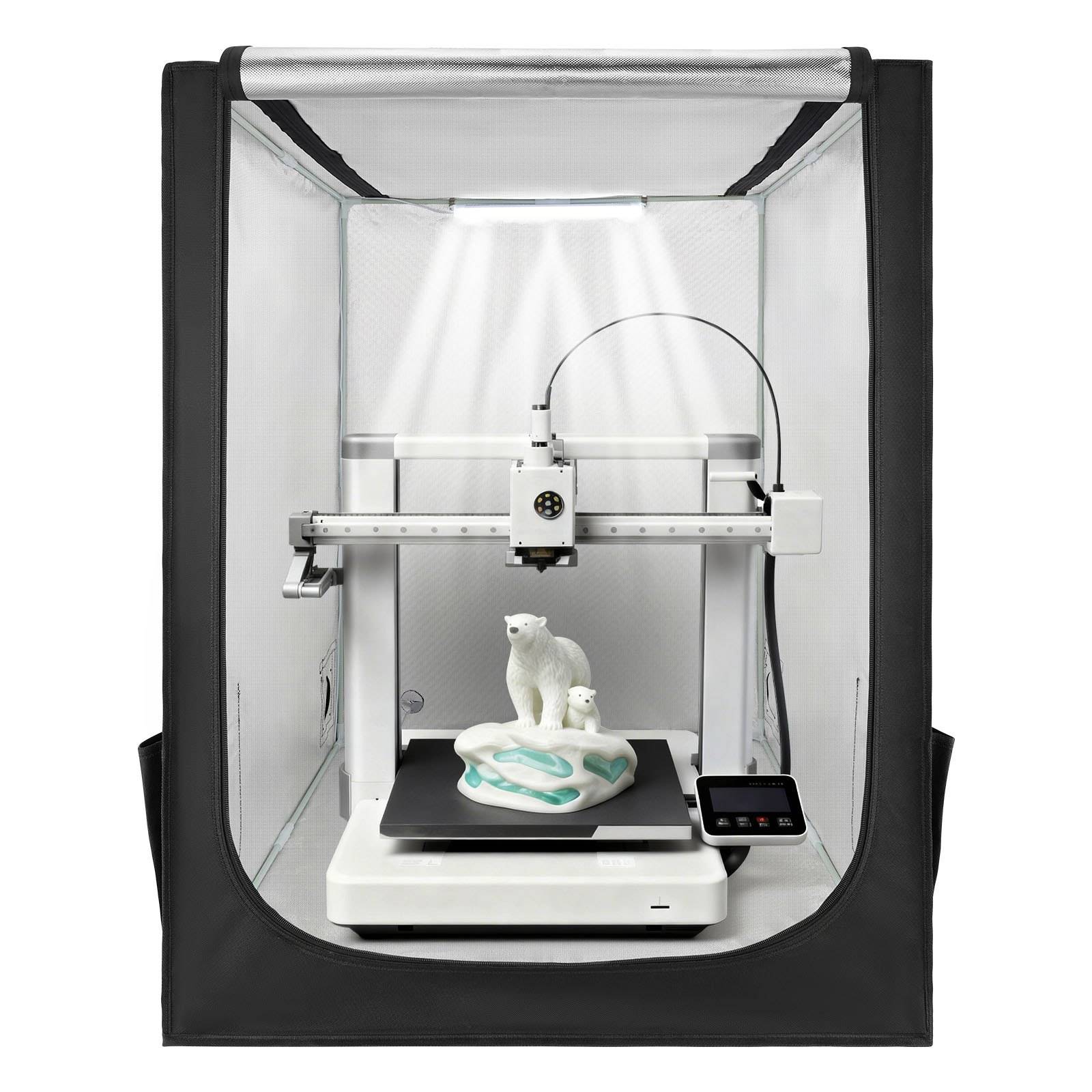 Ein geschlossener 3D-Drucker druckt eine weiße Eisbärfigur auf einer schwarzen Druckplattform in einem zeltartigen Gehäuse.