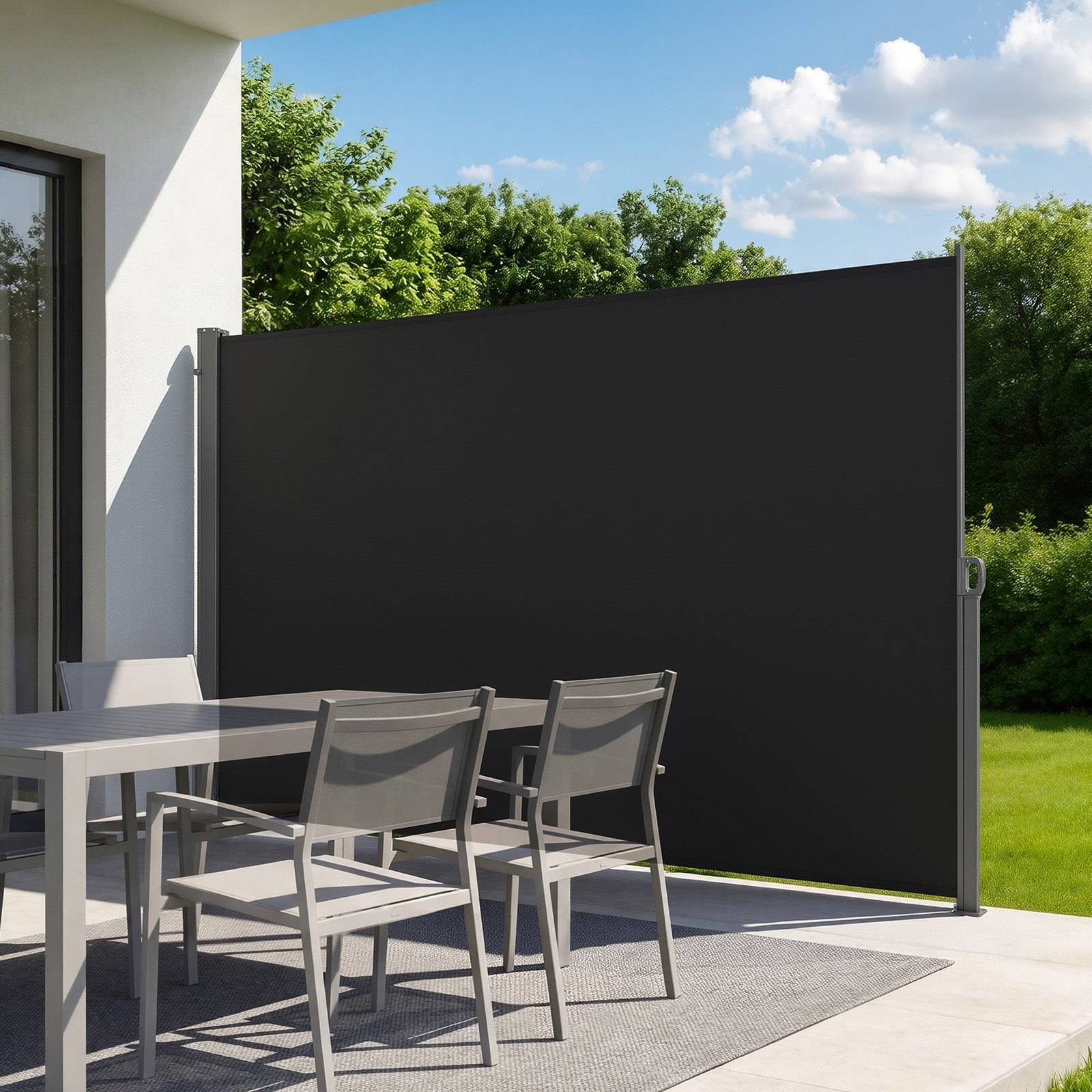 Terrasse mit grauem Outdoor-Esszimmer neben einem großen dunklen Sichtschutz, der einen geschützten Sitzbereich auf einer sonnigen Terrasse schafft.
